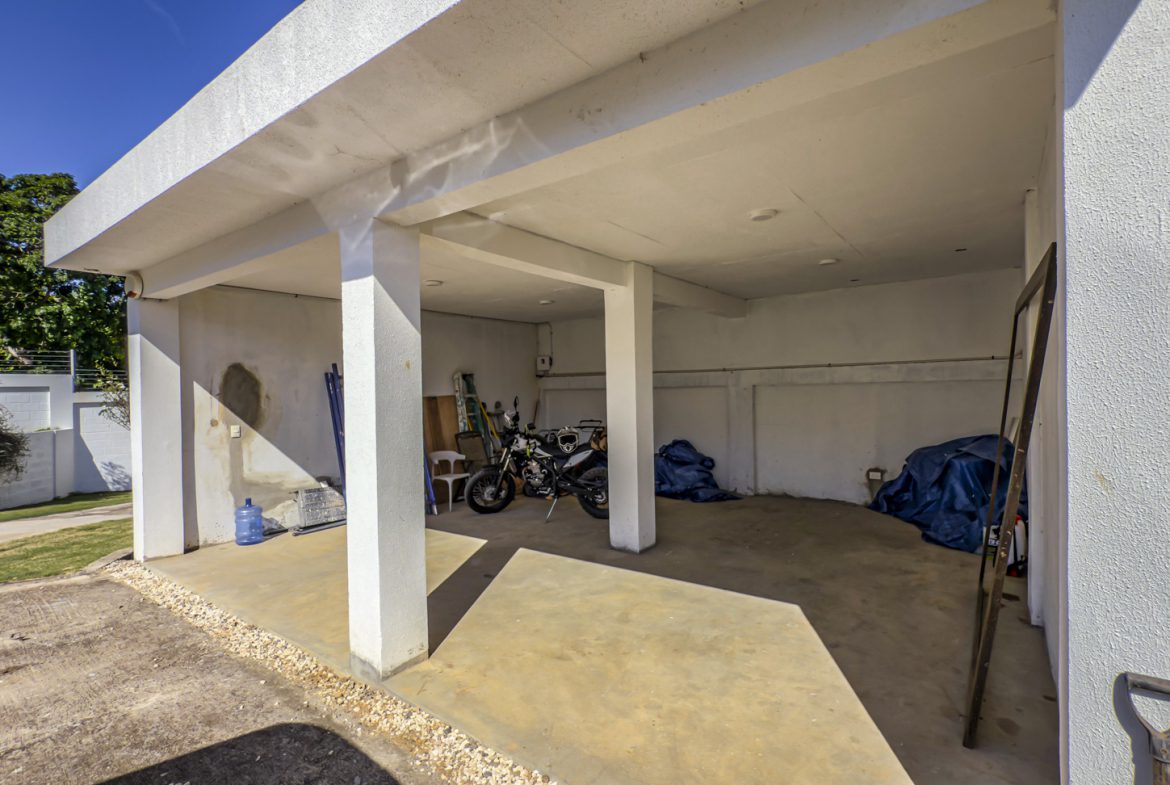 buyDRproperty Open carport with motorcycle, tools, and blue tarps in La Mulata villa. Sosua Real Estate