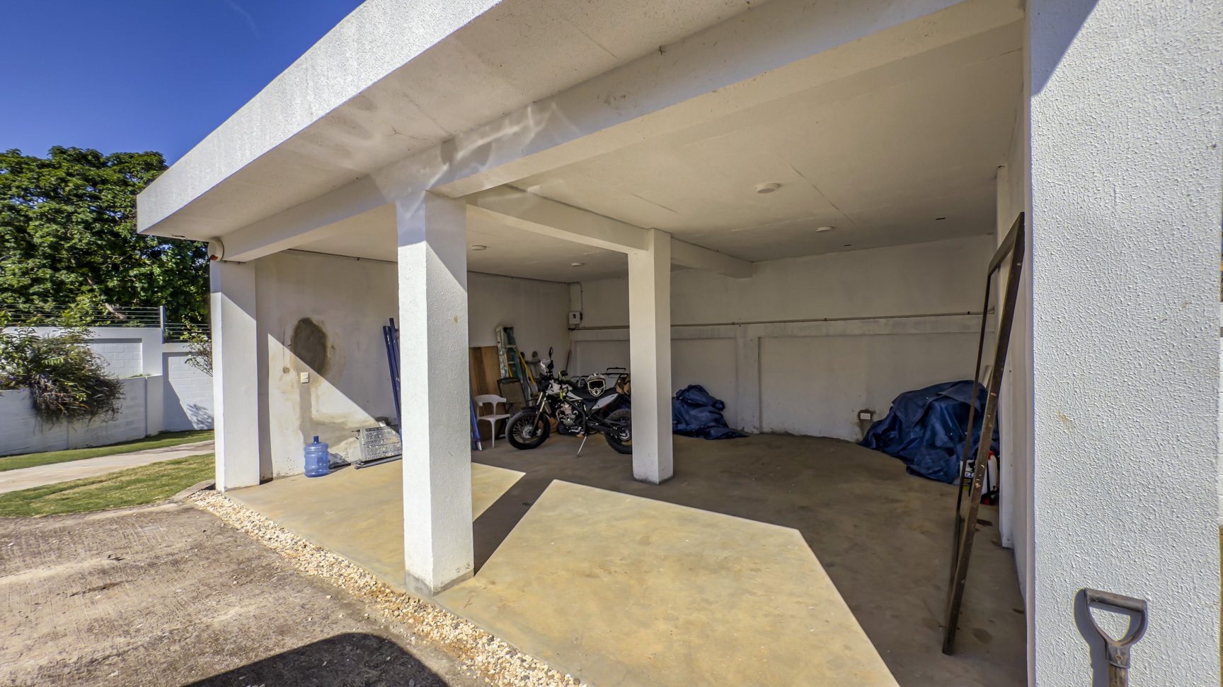 buyDRproperty Open carport with motorcycle, tools, and blue tarps in La Mulata villa. Sosua Real Estate
