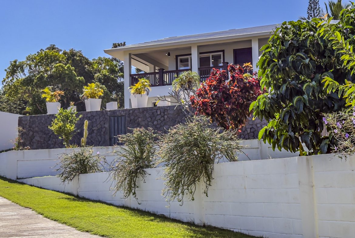 buyDRproperty La Mulata villa with 3 bedrooms, showcasing tropical landscaping and white exterior walls. Sosua Real Estate