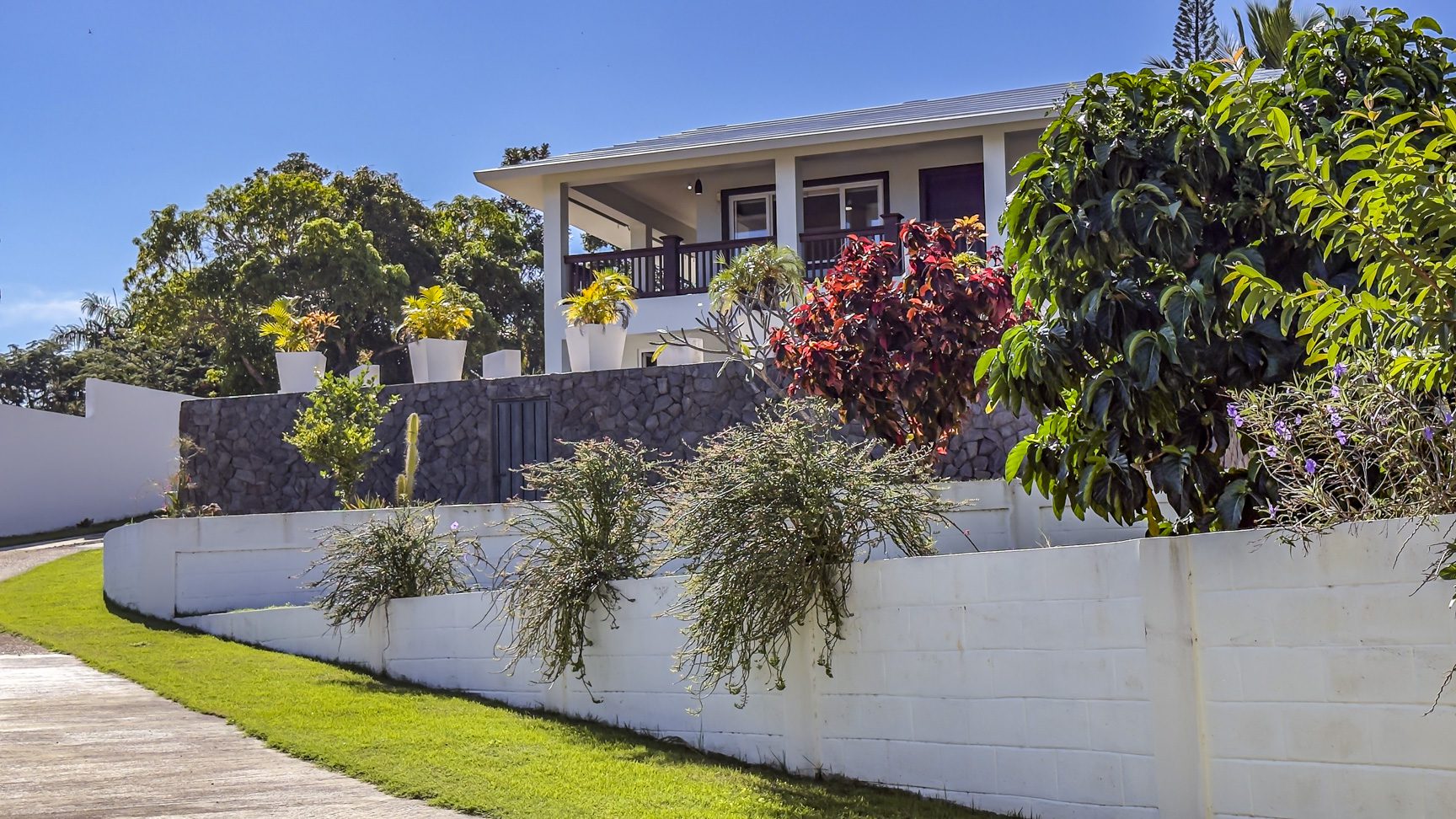 buyDRproperty La Mulata villa with 3 bedrooms, showcasing tropical landscaping and white exterior walls. Sosua Real Estate