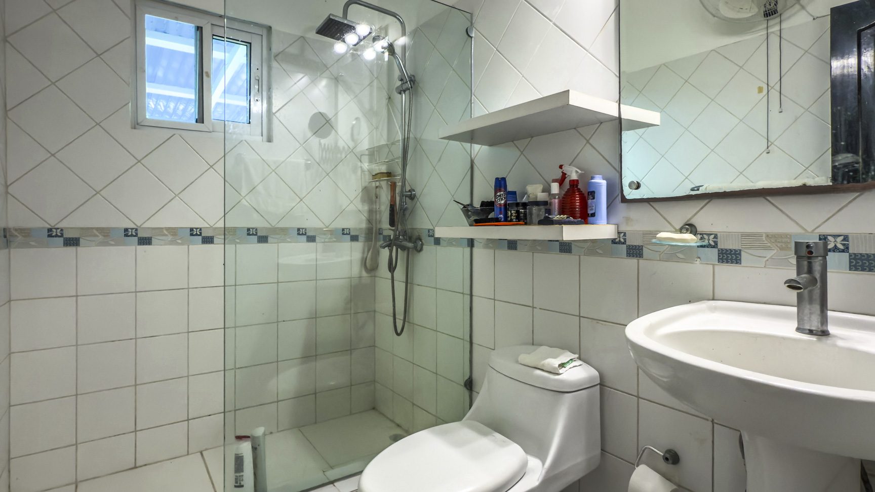 buyDRproperty Bathroom in Colibri villa with white tile, shower, toilet, and sink. Sosua Real Estate
