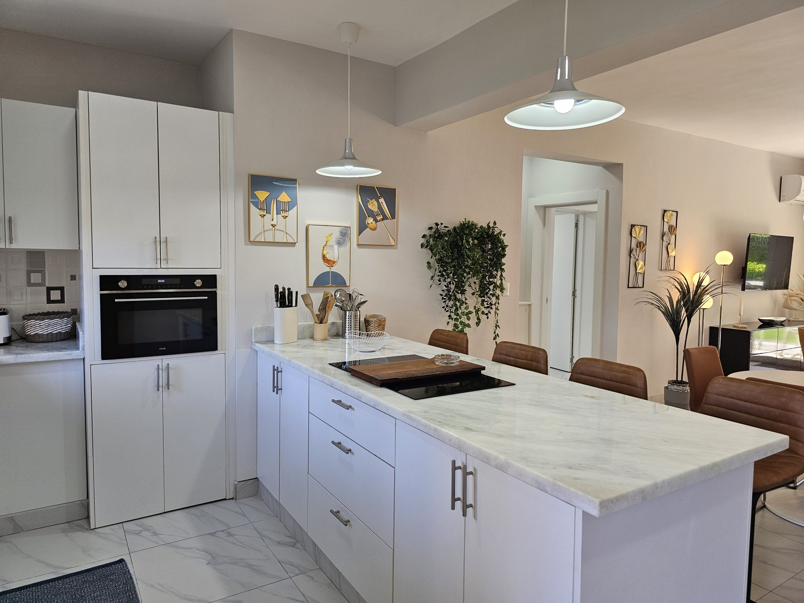 buyDRproperty Bright kitchen with white cabinets, marble island, pendant lights, and modern art. Sosua Real Estate