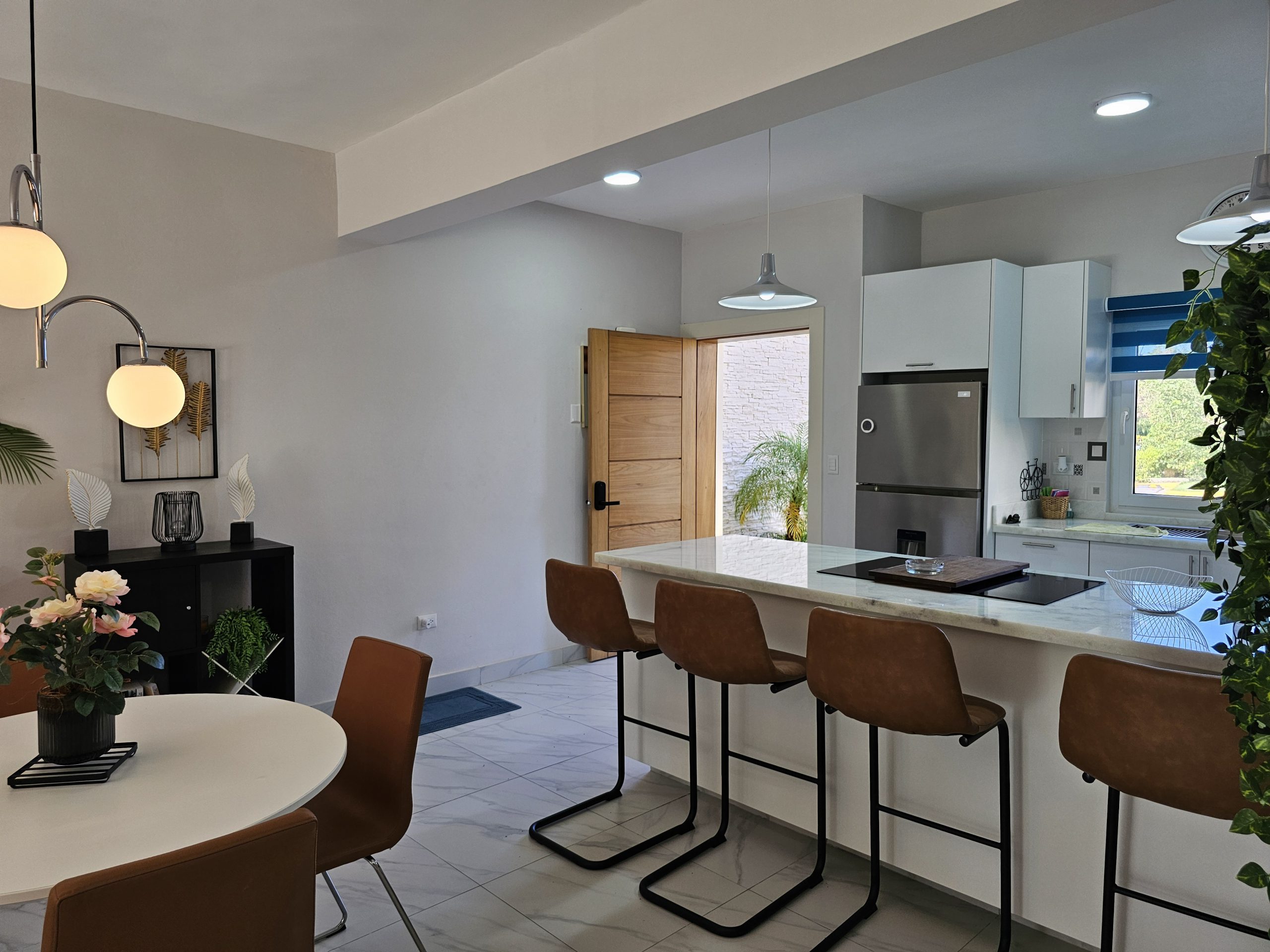 buyDRproperty Modern kitchen with island, bar stools, dining table, and sleek appliances. Bright, open concept design. Sosua Real Estate