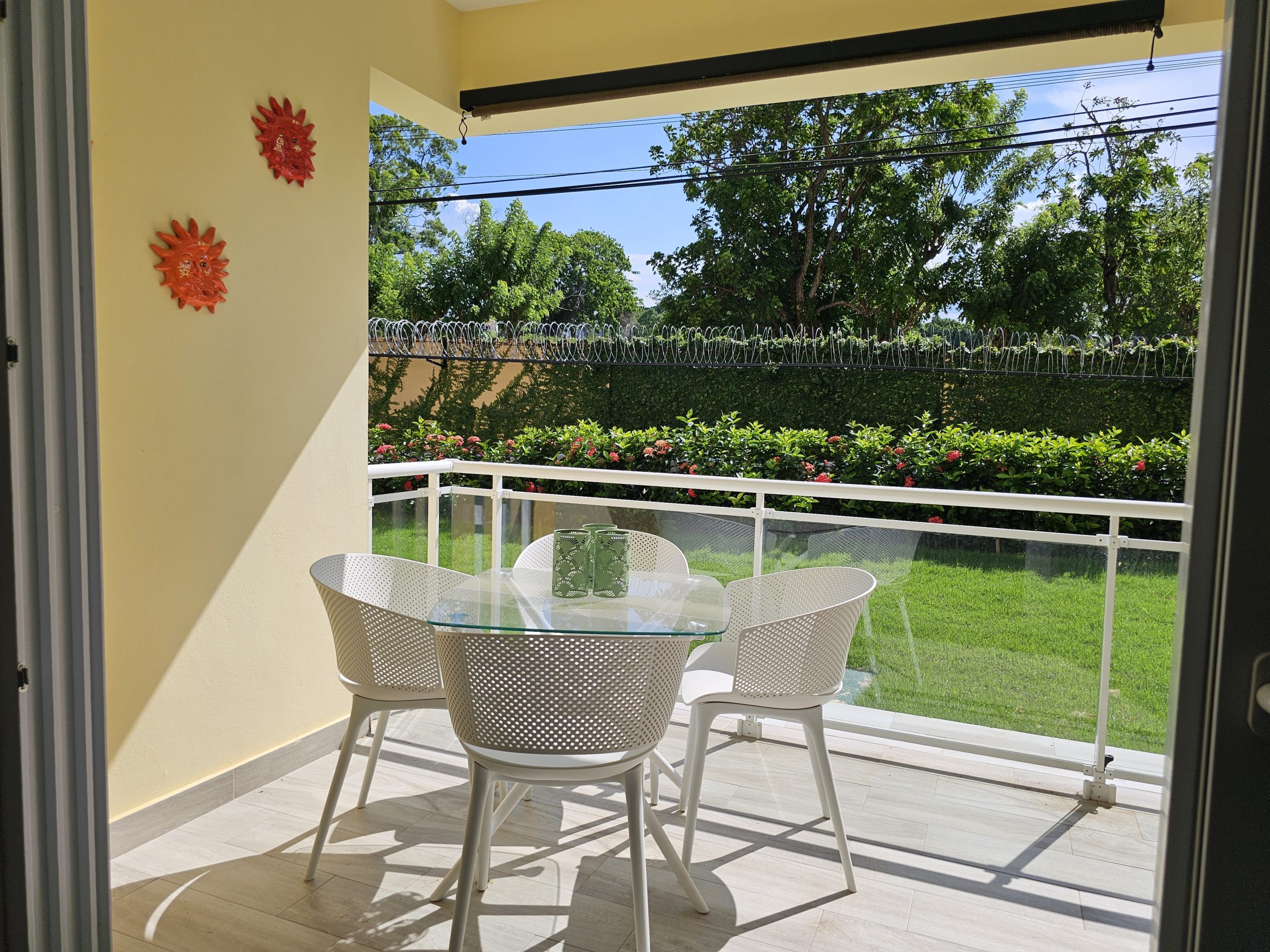 buyDRproperty Outdoor patio with table and chairs overlooking green lawn. Sosua Real Estate