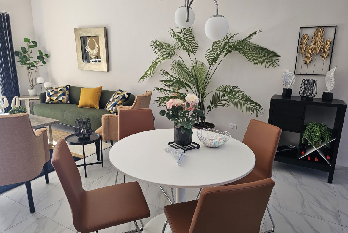 buyDRproperty Modern living room with green sofa, round white dining table, and brown chairs. Interior design. Sosua Real Estate