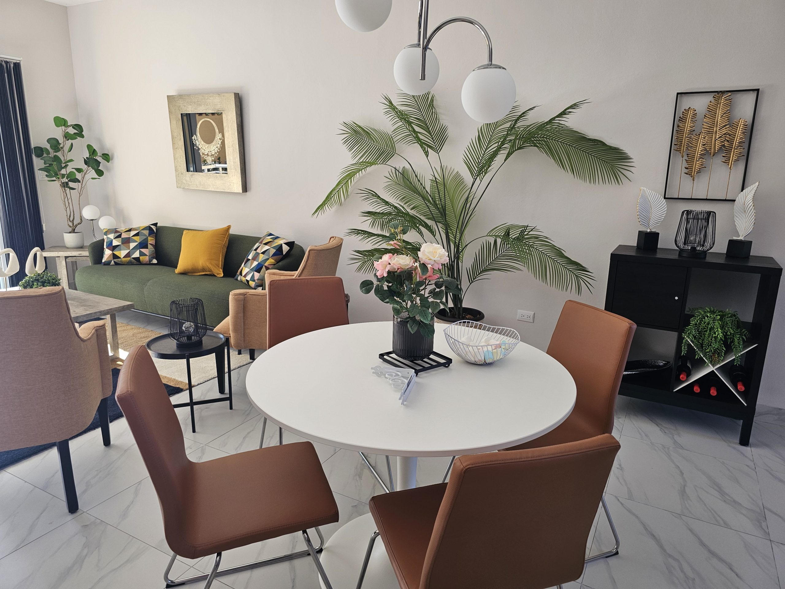 buyDRproperty Modern living room with green sofa, round white dining table, and brown chairs. Interior design. Sosua Real Estate