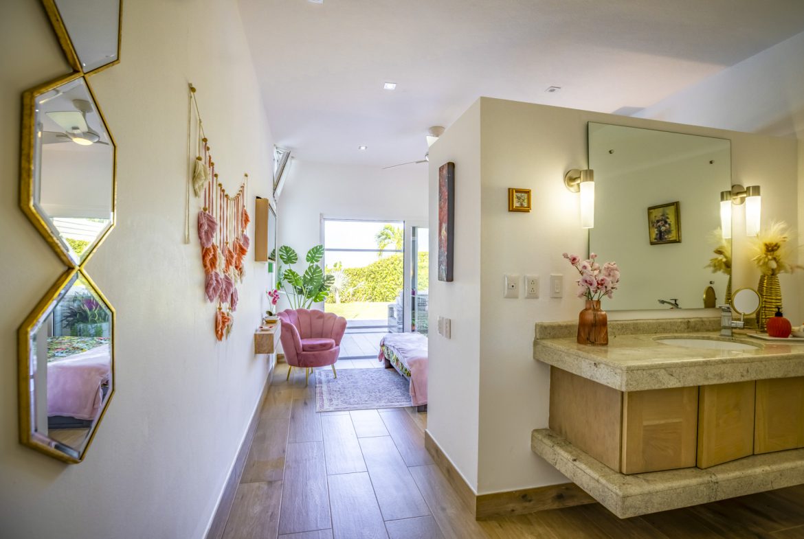 buyDRproperty Hallway leading to a bedroom with pink armchair and garden view. Sosua Real Estate
