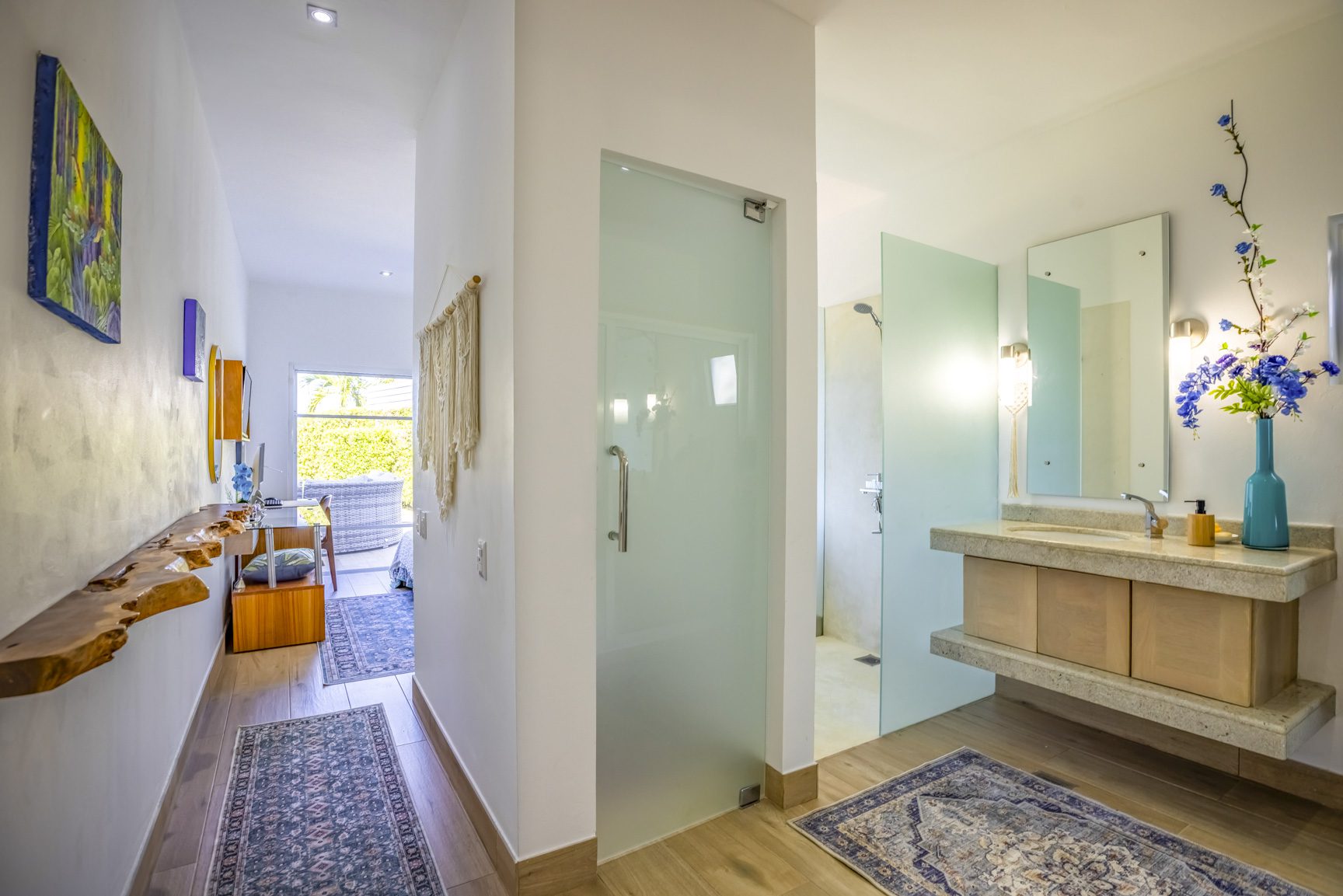 buyDRproperty Modern bathroom with floating vanity, glass shower, and hallway with rustic wood shelf. Sosua Real Estate