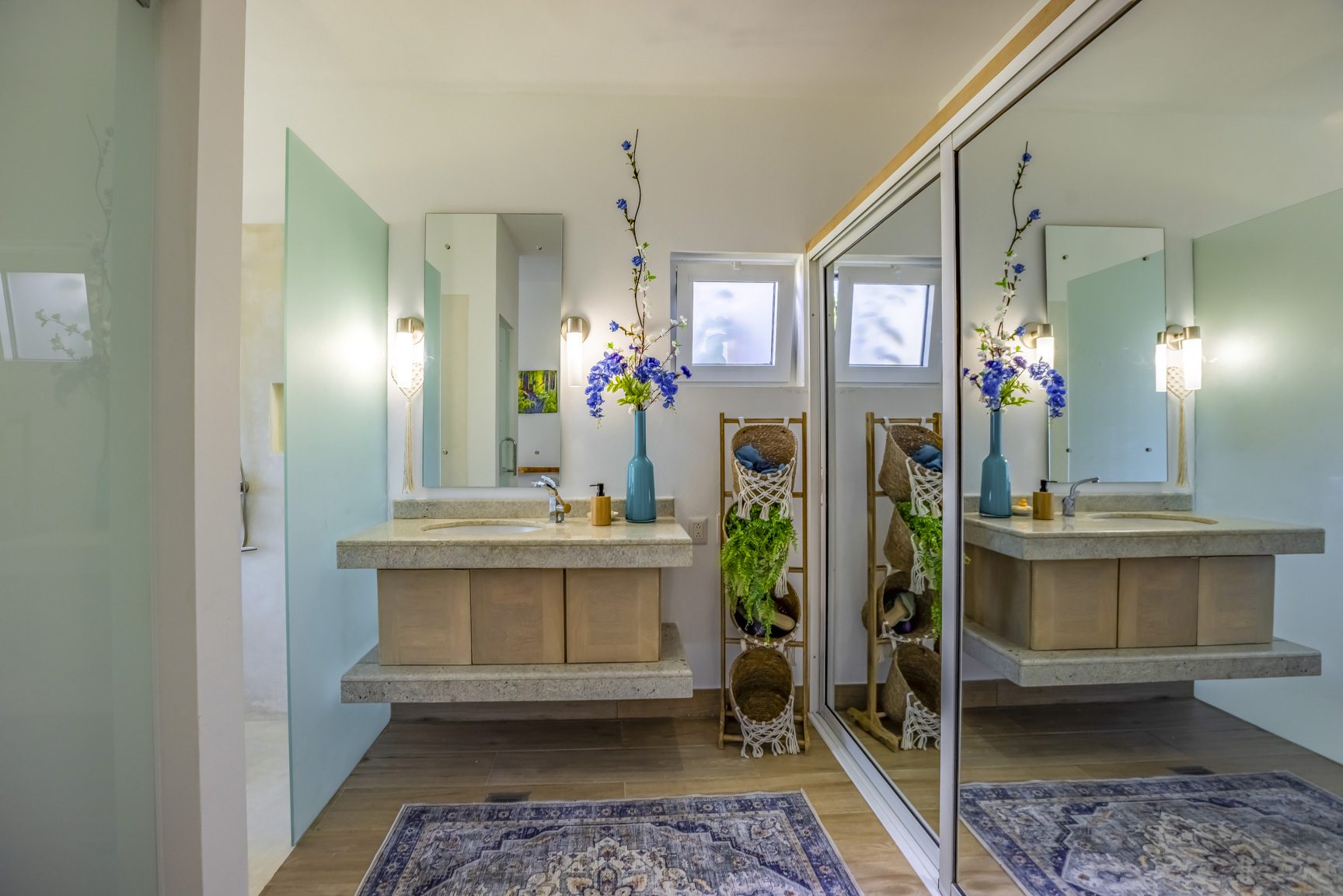 buyDRproperty Modern bathroom with floating vanity, mirror, blue flowers, and sliding closet doors. Sosua Real Estate