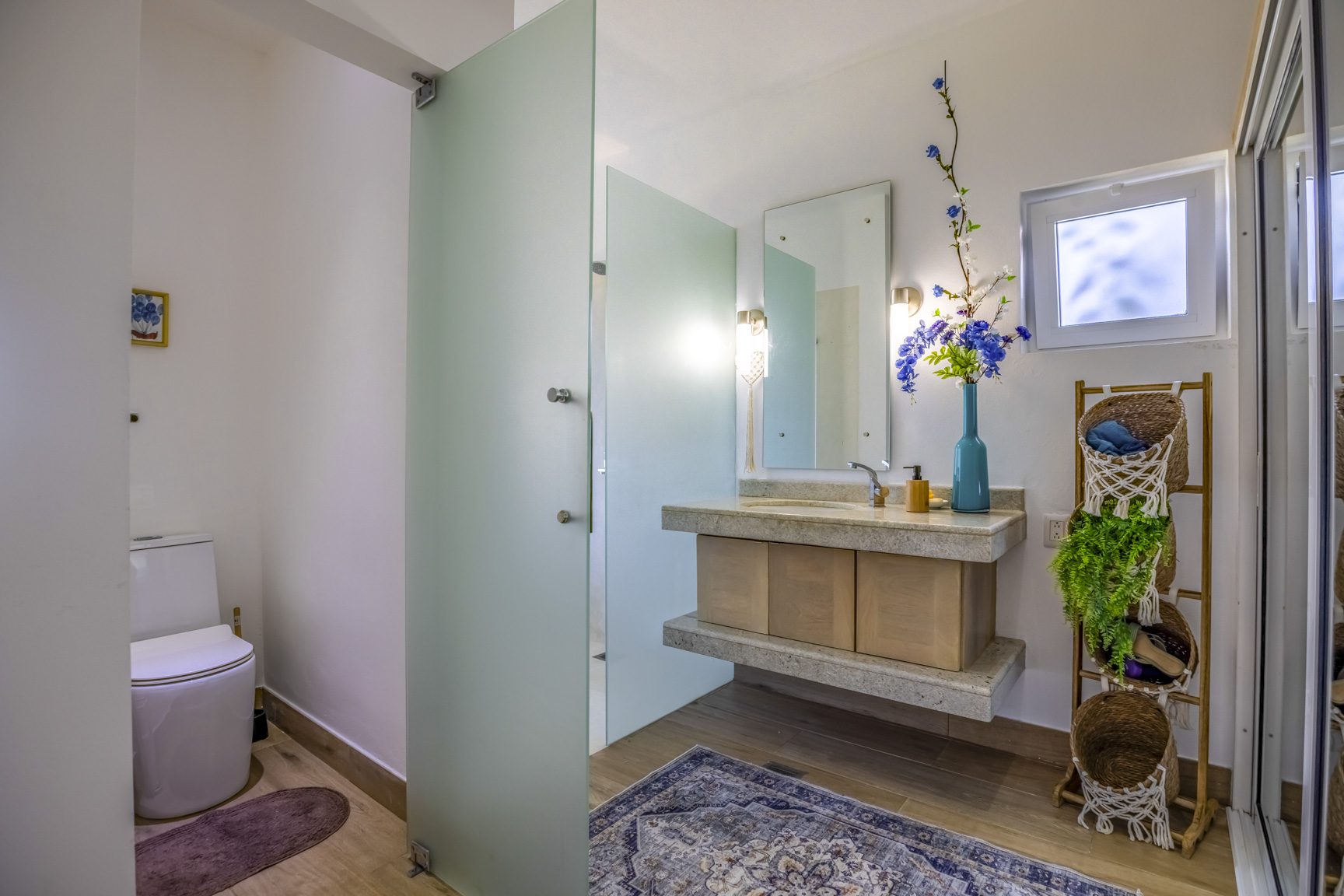 buyDRproperty Modern bathroom with frosted glass door, floating vanity, and blue accents. Sosua Real Estate