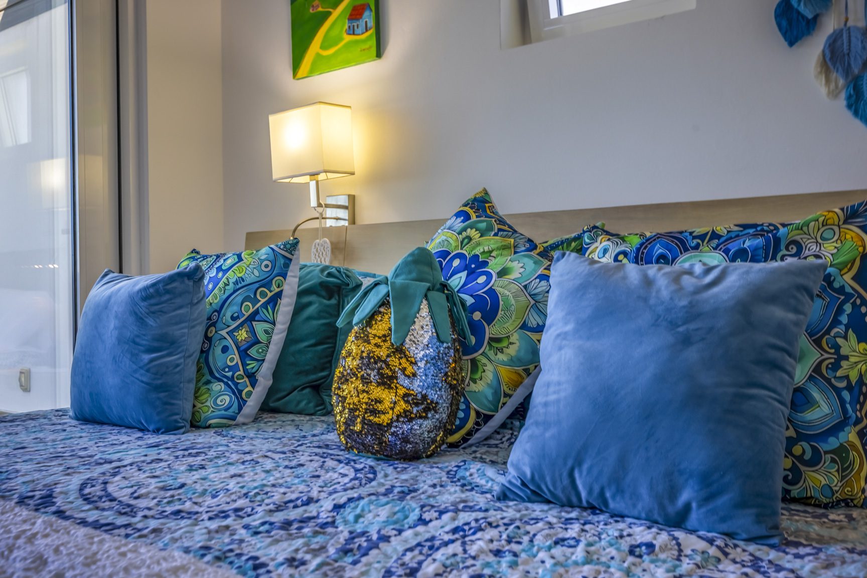 buyDRproperty Cozy bed with blue and turquoise patterned bedding and decorative pillows. Sosua Real Estate