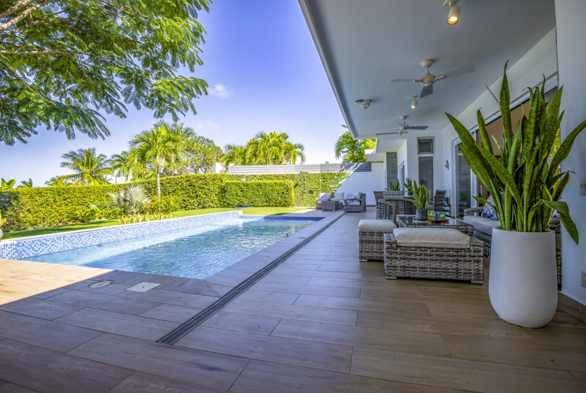 buyDRproperty Luxury villa pool with outdoor lounge area and lush landscaping. Sosua Real Estate