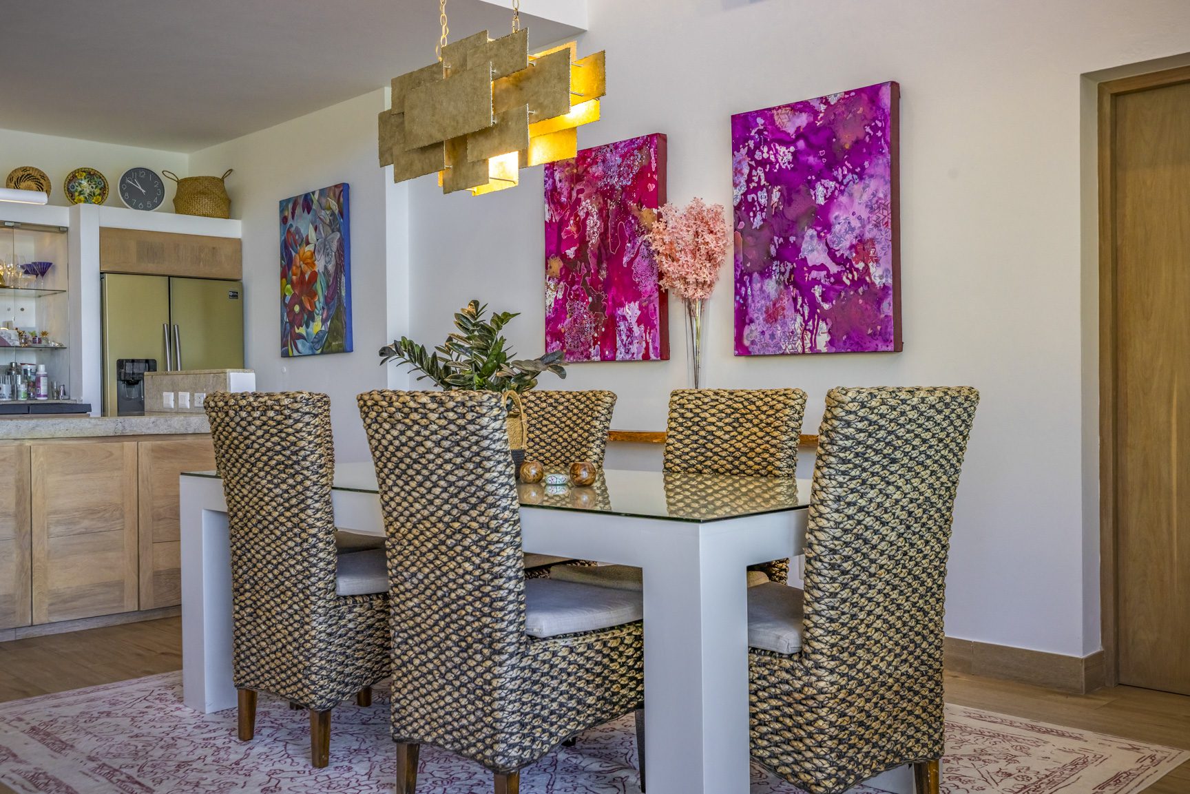 buyDRproperty Dining room with woven chairs, glass table, and vibrant pink artwork. Sosua Real Estate