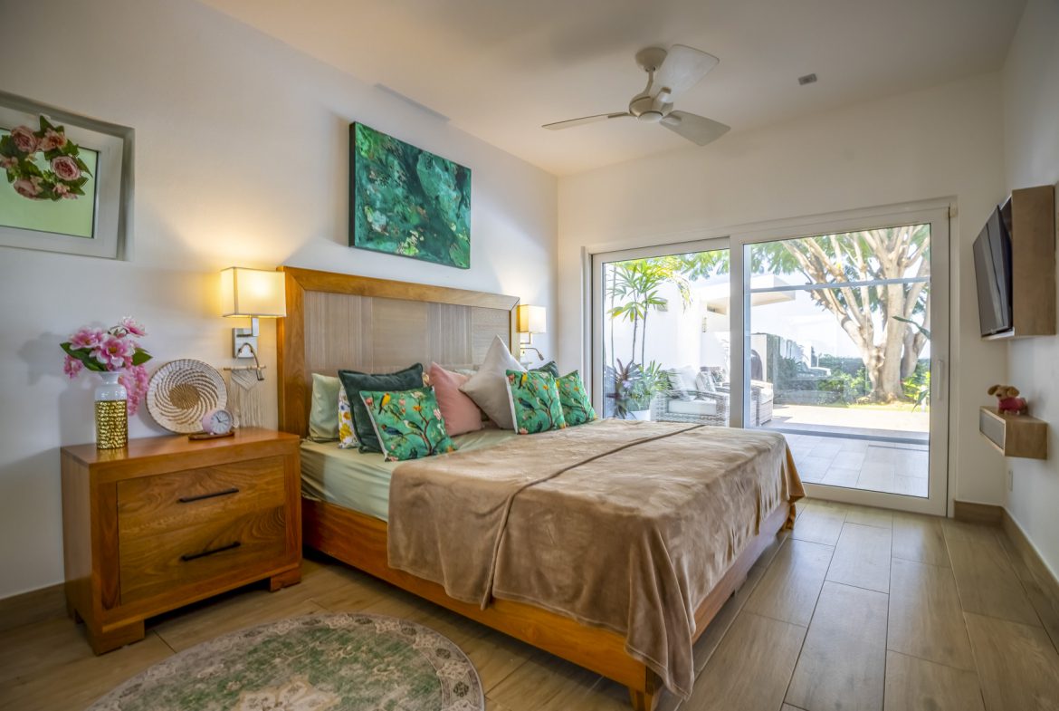 buyDRproperty Bright bedroom with king bed, wood furniture, and sliding glass doors to a patio. Sosua Real Estate