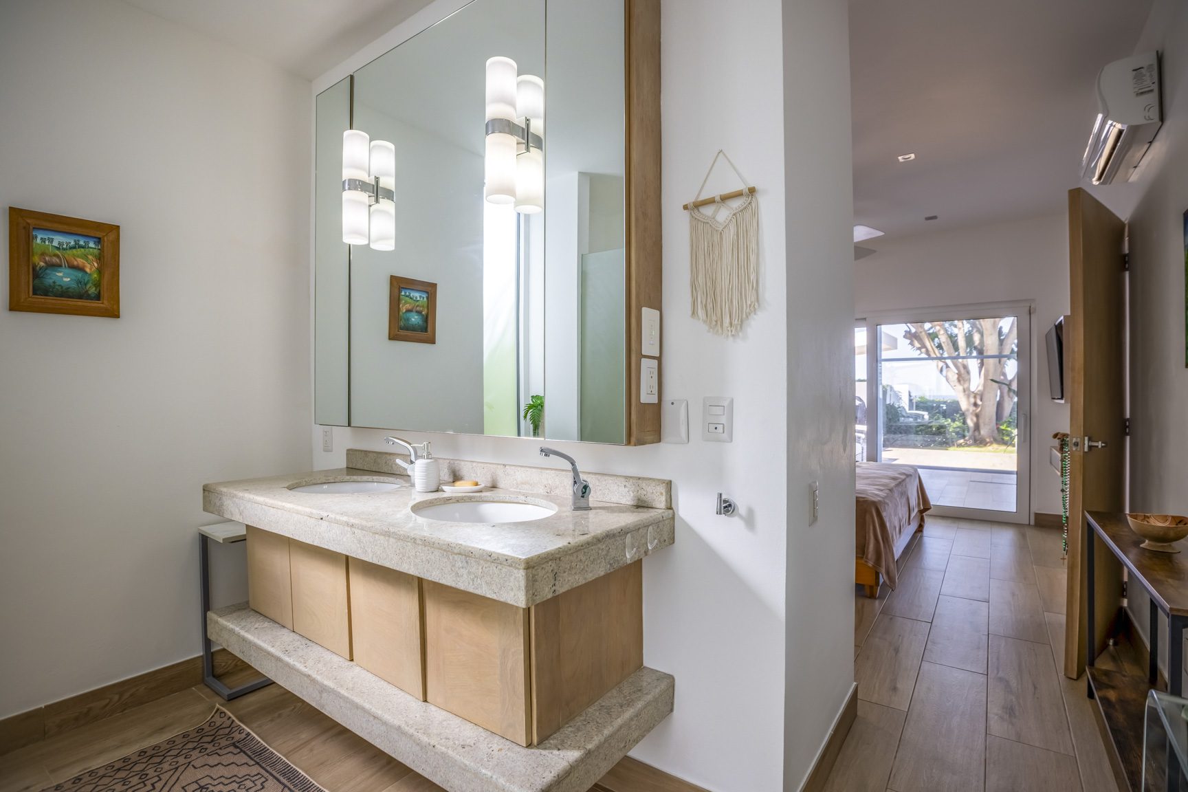buyDRproperty Modern bathroom with double vanity, stone countertop, and doorway to bedroom. Sosua Real Estate