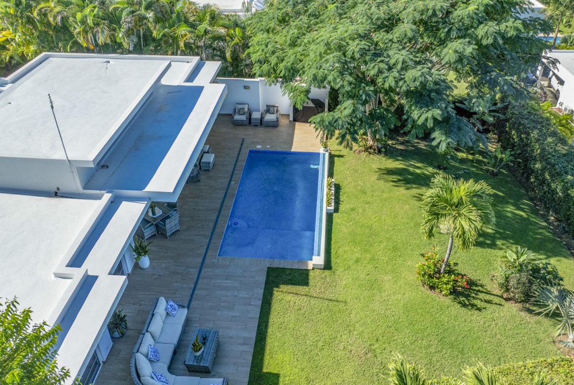 buyDRproperty Aerial view of a Caribbean villa with a luxury pool surrounded by lush greenery. Sosua Real Estate