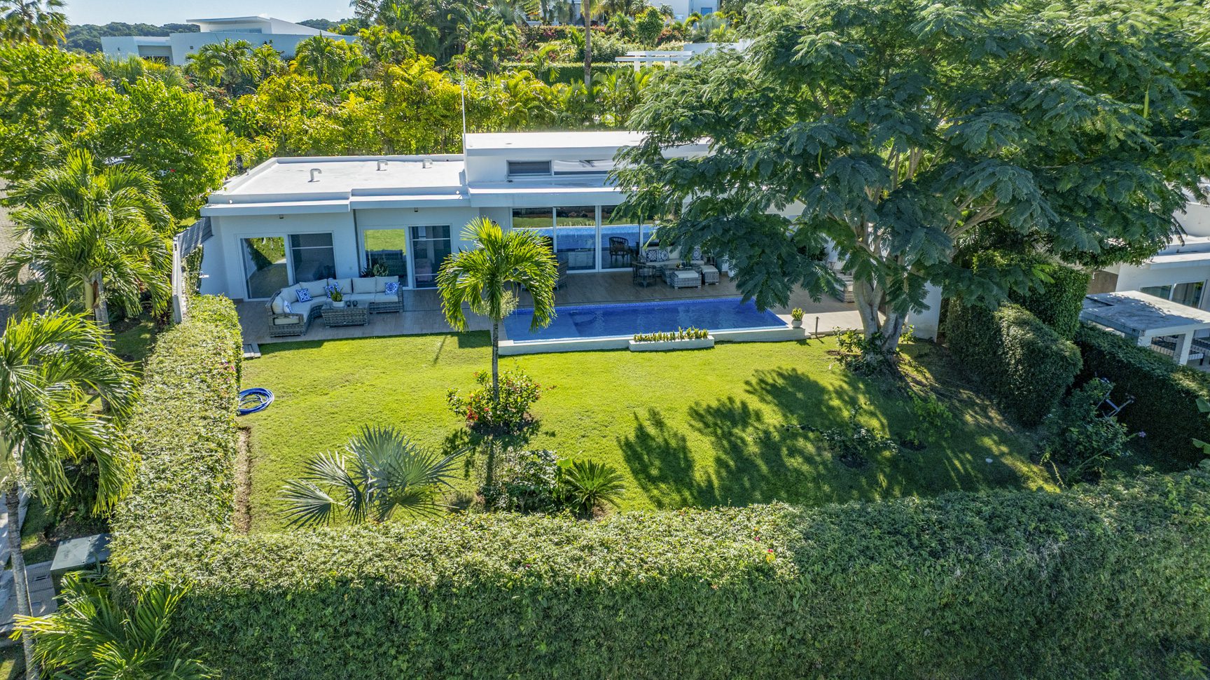 buyDRproperty Luxury villa with pool and lush green lawn surrounded by manicured hedges. Sosua Real Estate