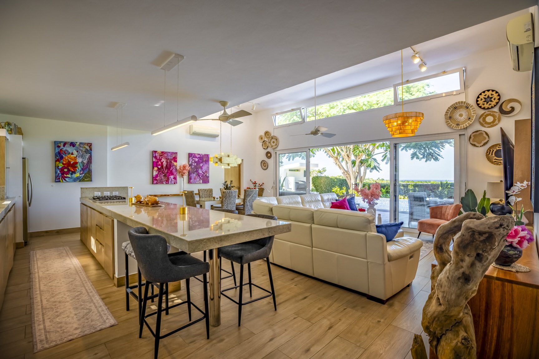 buyDRproperty Bright, open-concept living room with kitchen island, beige sofa, and patio view. Sosua Real Estate