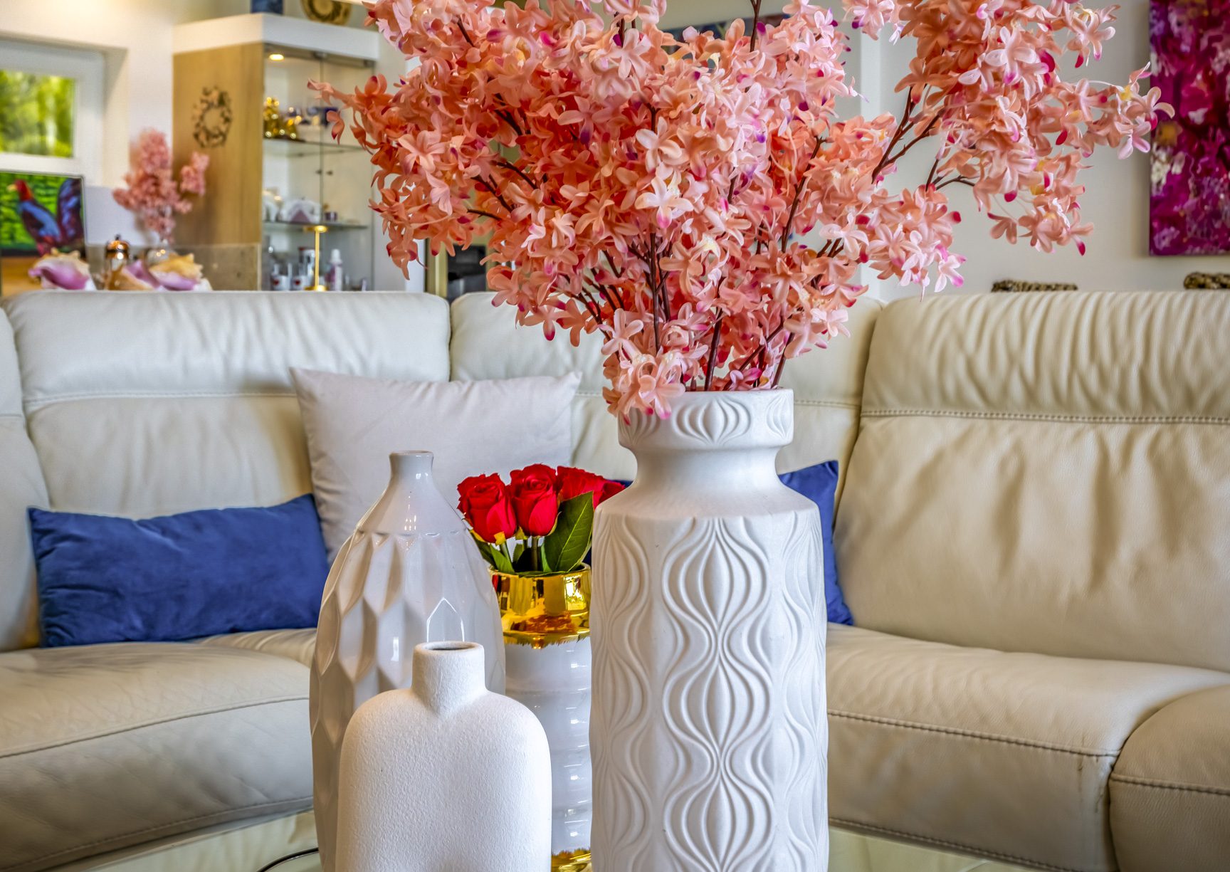 buyDRproperty Vases with flowers on a glass table in front of a white leather couch Sosua Real Estate