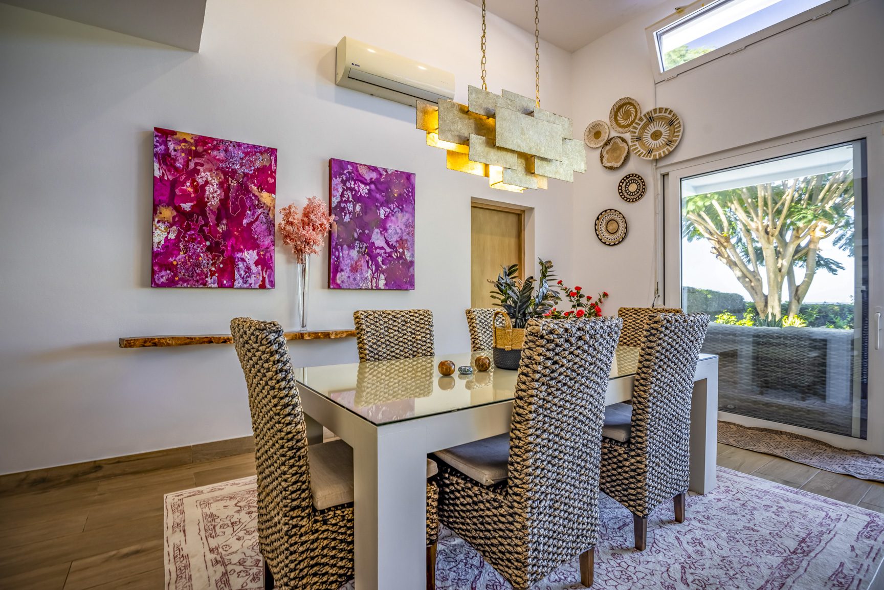 buyDRproperty Bright dining room featuring a white table, wicker chairs, and vibrant pink abstract art on the wall. Sosua Real Estate
