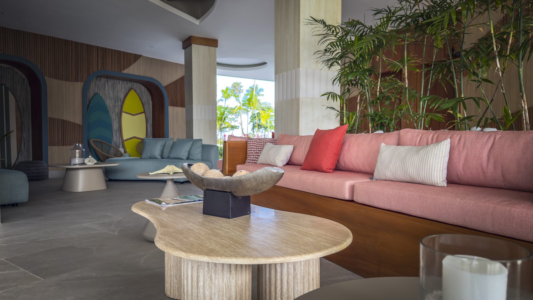 buyDRproperty Stylish hotel lobby with colorful sofas, surfboard art, and tropical plants. Modern resort interior design. Sosua Real Estate
