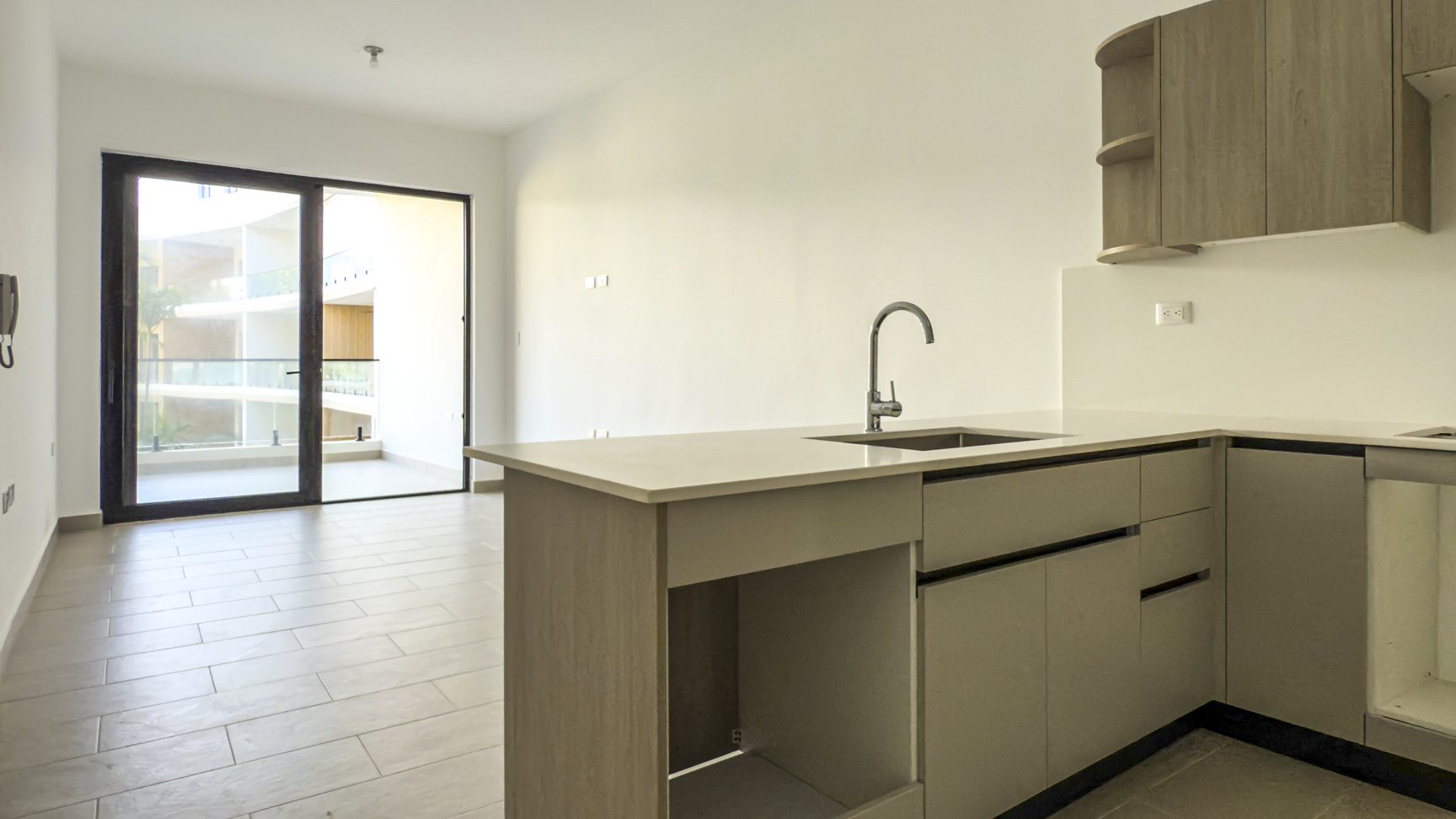buyDRproperty Modern apartment kitchen with sleek cabinets, sink, and balcony. Sosua Real Estate