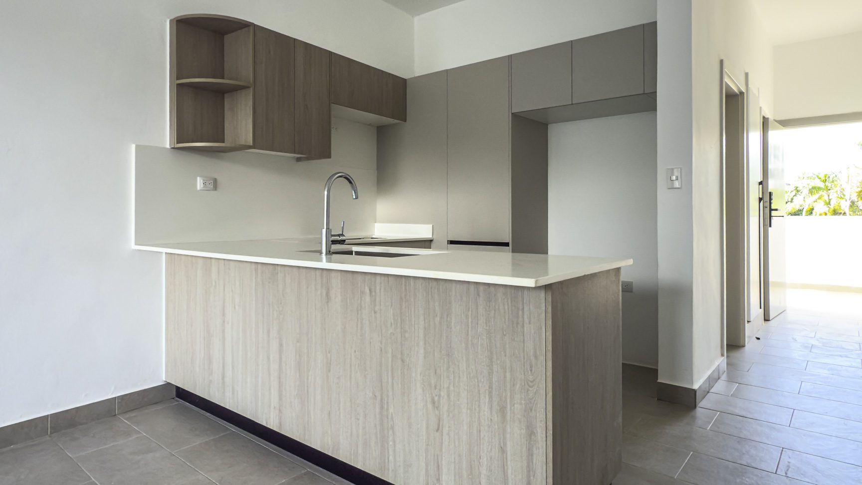 buyDRproperty Modern kitchen with light wood cabinets, white countertops, and tile flooring. Minimalist design. Sosua Real Estate