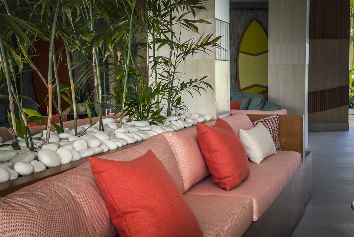 buyDRproperty Stylish lobby with coral sofa, orange pillows, bamboo, and white stones. Tropical resort interior design. Sosua Real Estate