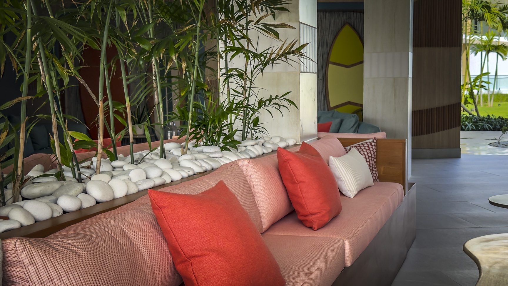 buyDRproperty Stylish lobby with coral sofa, orange pillows, bamboo, and white stones. Tropical resort interior design. Sosua Real Estate