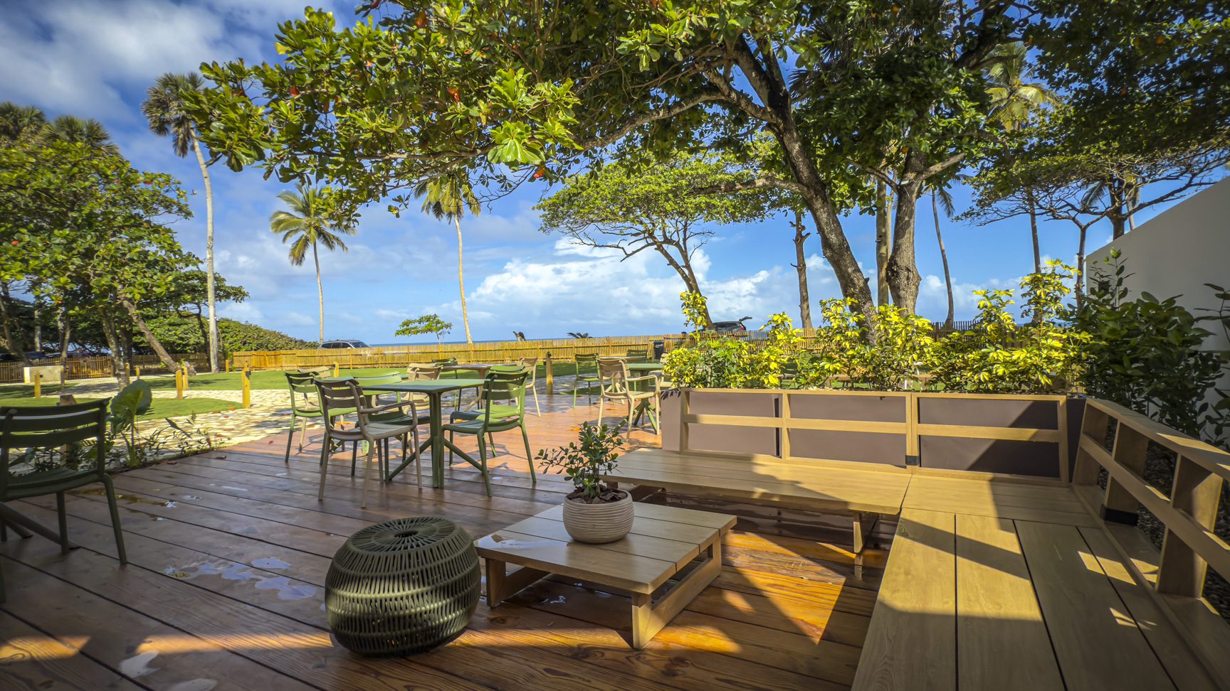 buyDRproperty Outdoor patio with wooden furniture and palm trees overlooking the ocean. Sosua Real Estate