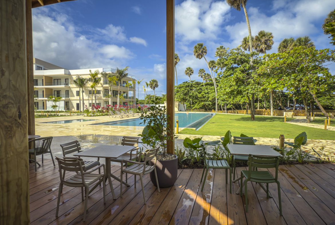buyDRproperty Outdoor dining area overlooking a pool and tropical landscape at a resort. Sosua Real Estate