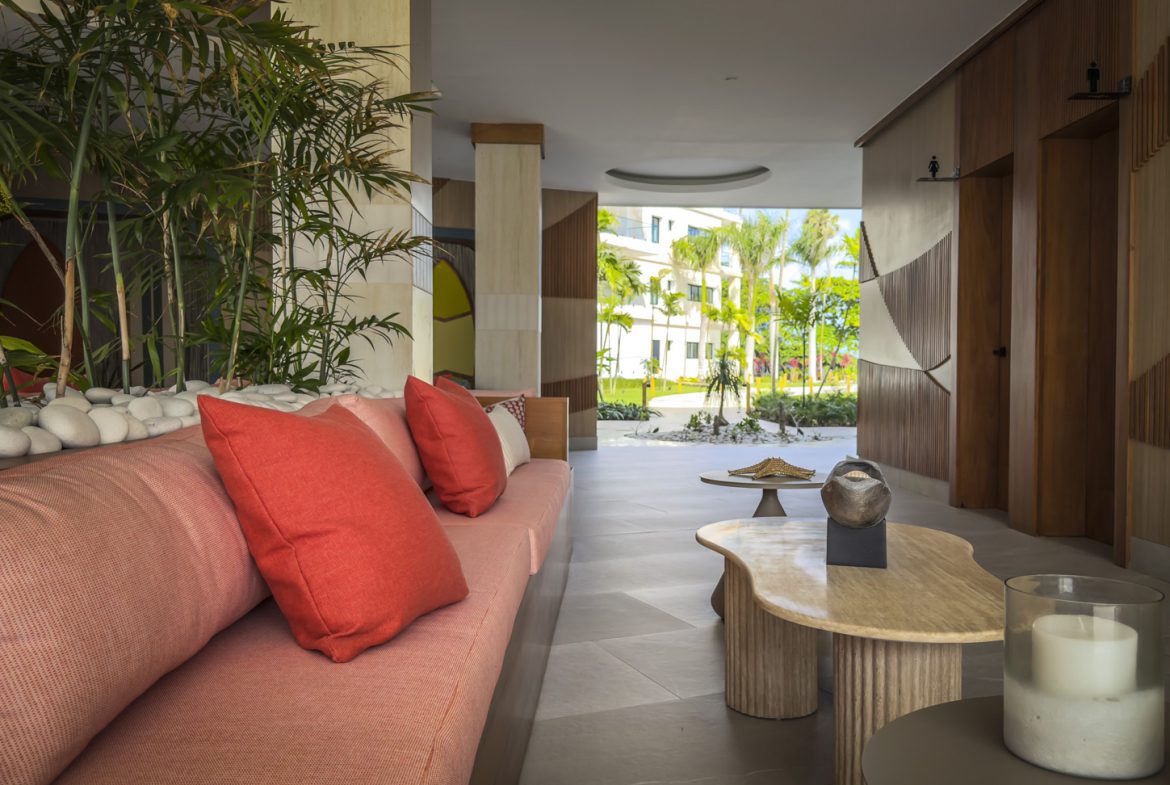 buyDRproperty Elegant hotel lobby with coral sofa, tropical plants, and view to the garden. Sosua Real Estate