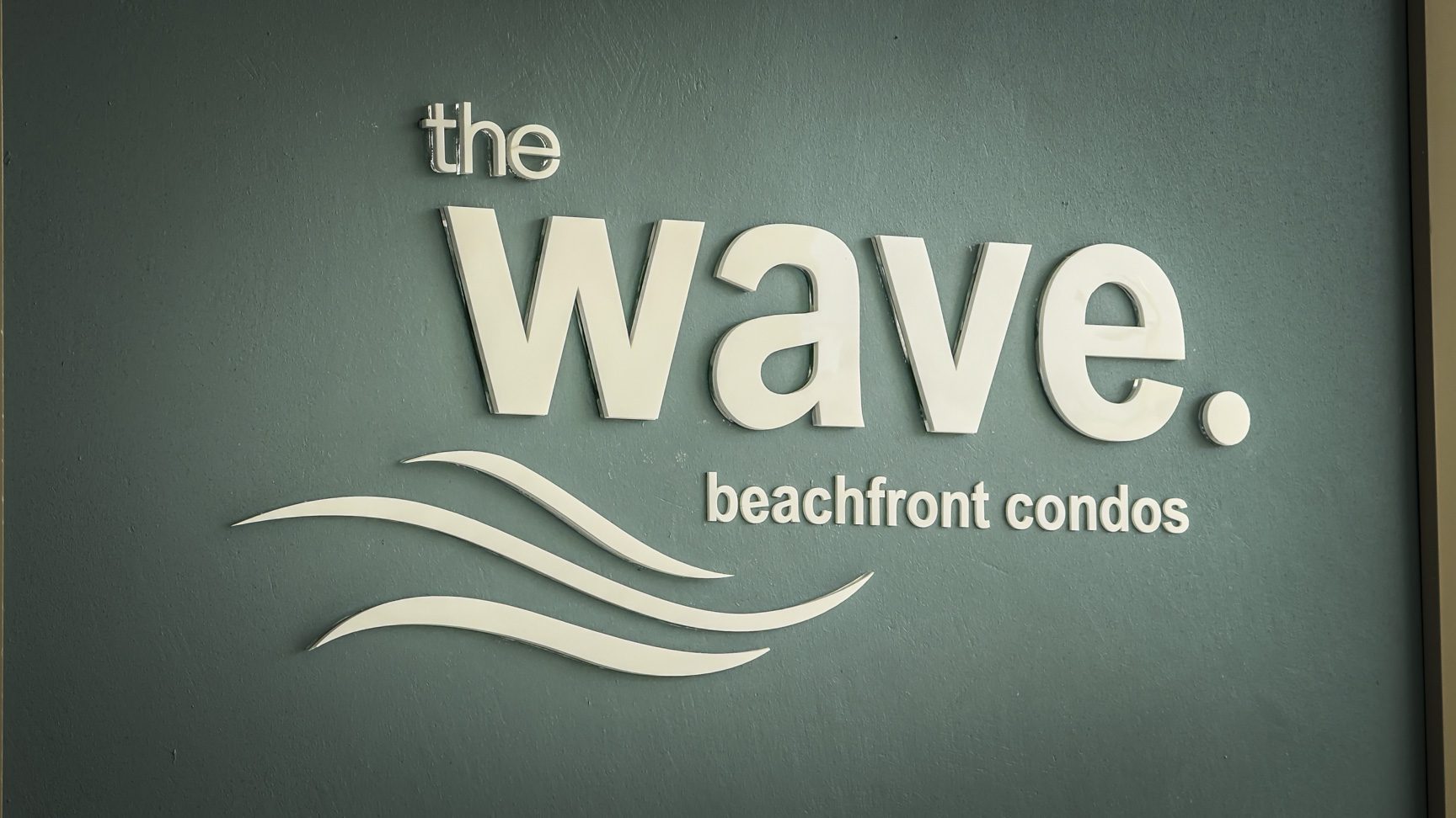 buyDRproperty The Wave beachfront condos sign with wave graphic. Sosua Real Estate