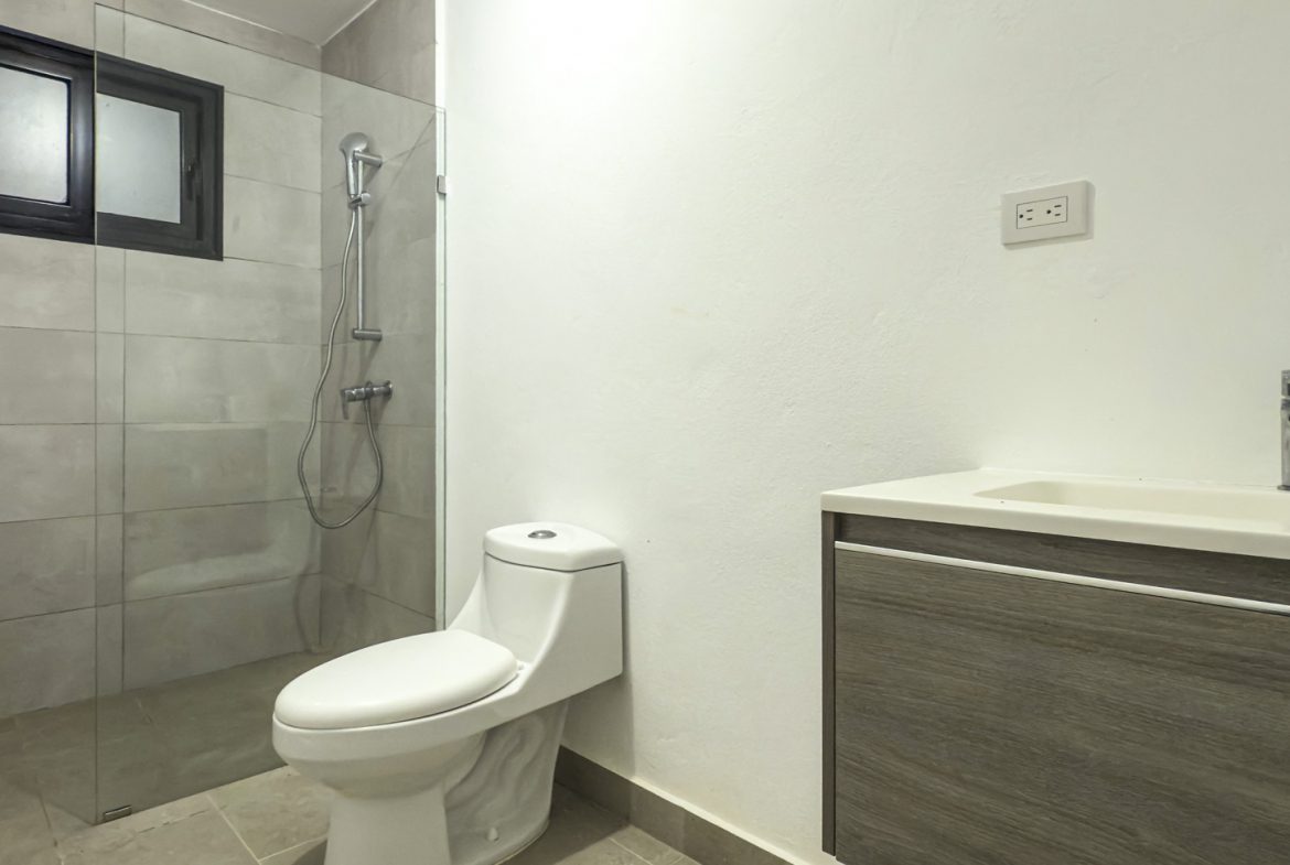 buyDRproperty Modern bathroom with walk-in shower, toilet, and vanity with sink. Clean, contemporary design. Sosua Real Estate