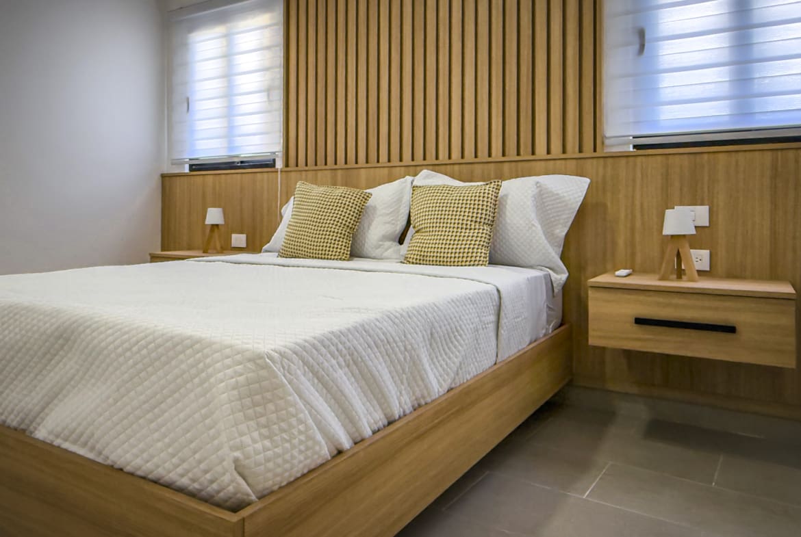 Oceanfront 2BR condo bedroom at The Wave, Cabarete, with modern wood accents.