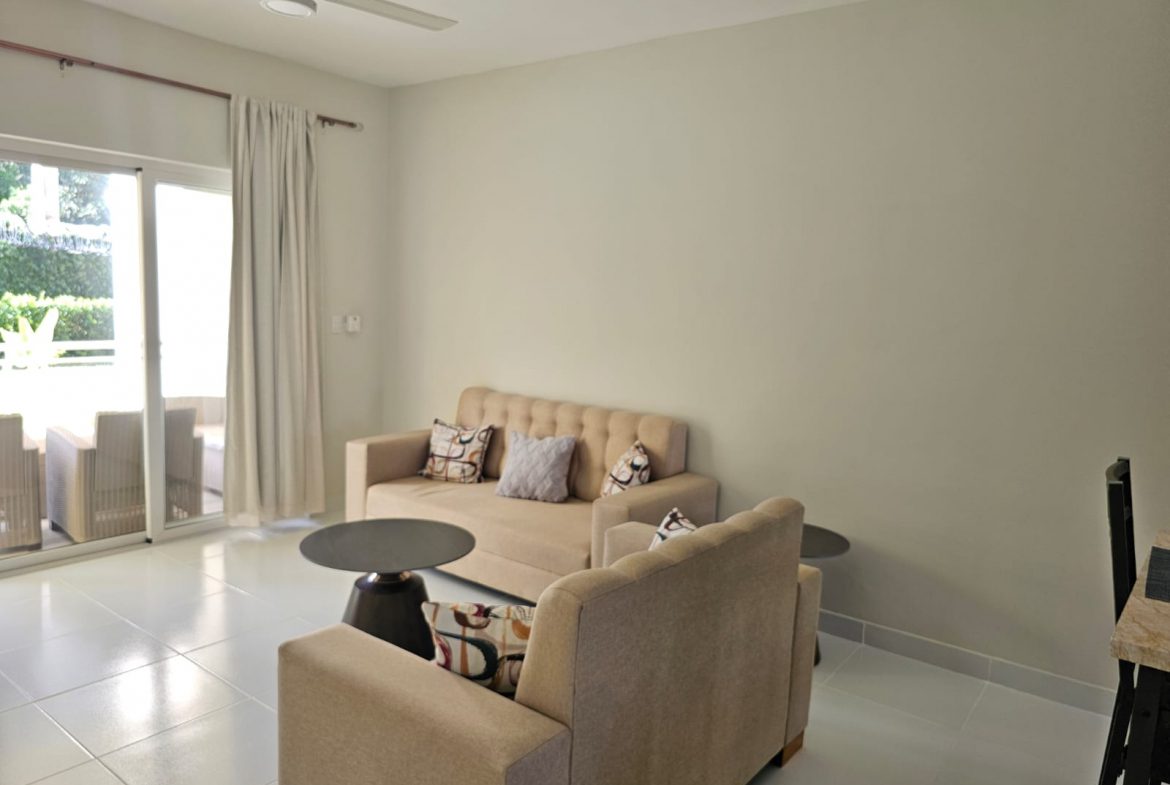 buyDRproperty Bright living room with beige sofa, armchair, and sliding glass doors to a patio. Sosua Real Estate