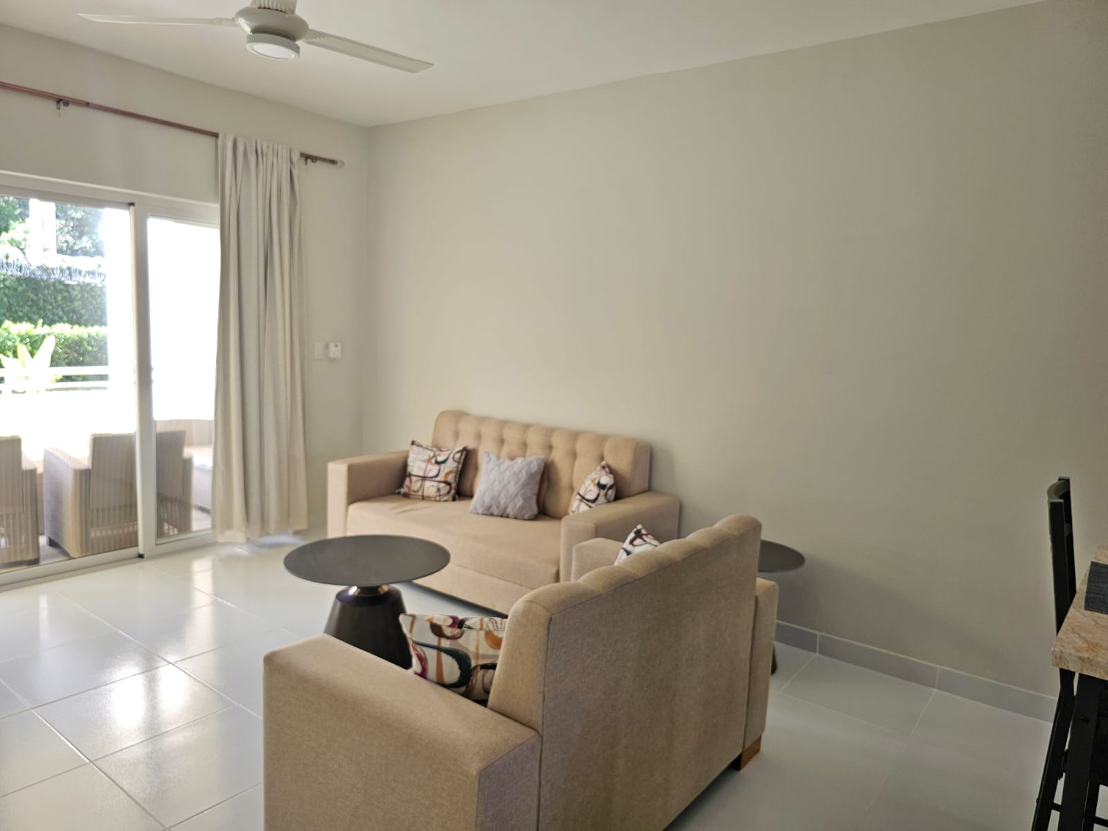 buyDRproperty Bright living room with beige sofa, armchair, and sliding glass doors to a patio. Sosua Real Estate