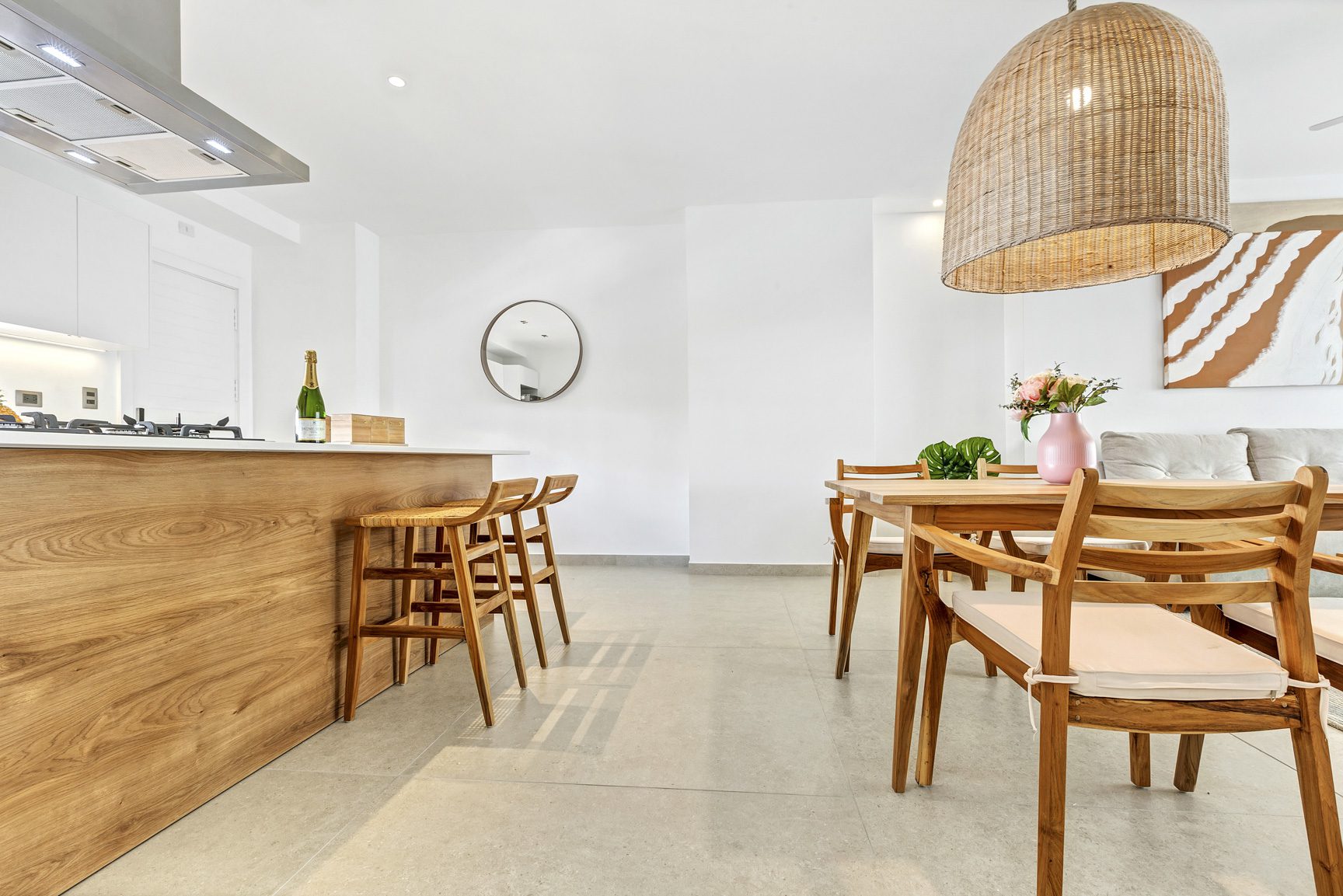 buyDRproperty Bright, modern dining area with wooden table, chairs, island, and woven pendant light. Sosua Real Estate