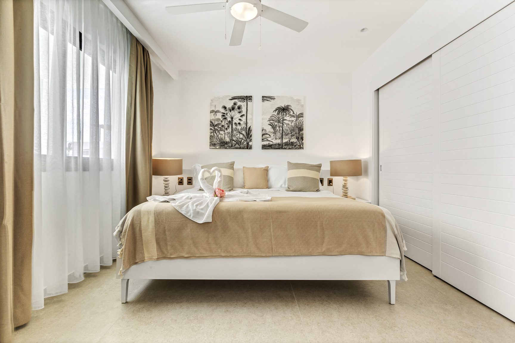 buyDRproperty Bright bedroom with king bed, palm tree art, and white linens. Modern coastal interior design. Sosua Real Estate