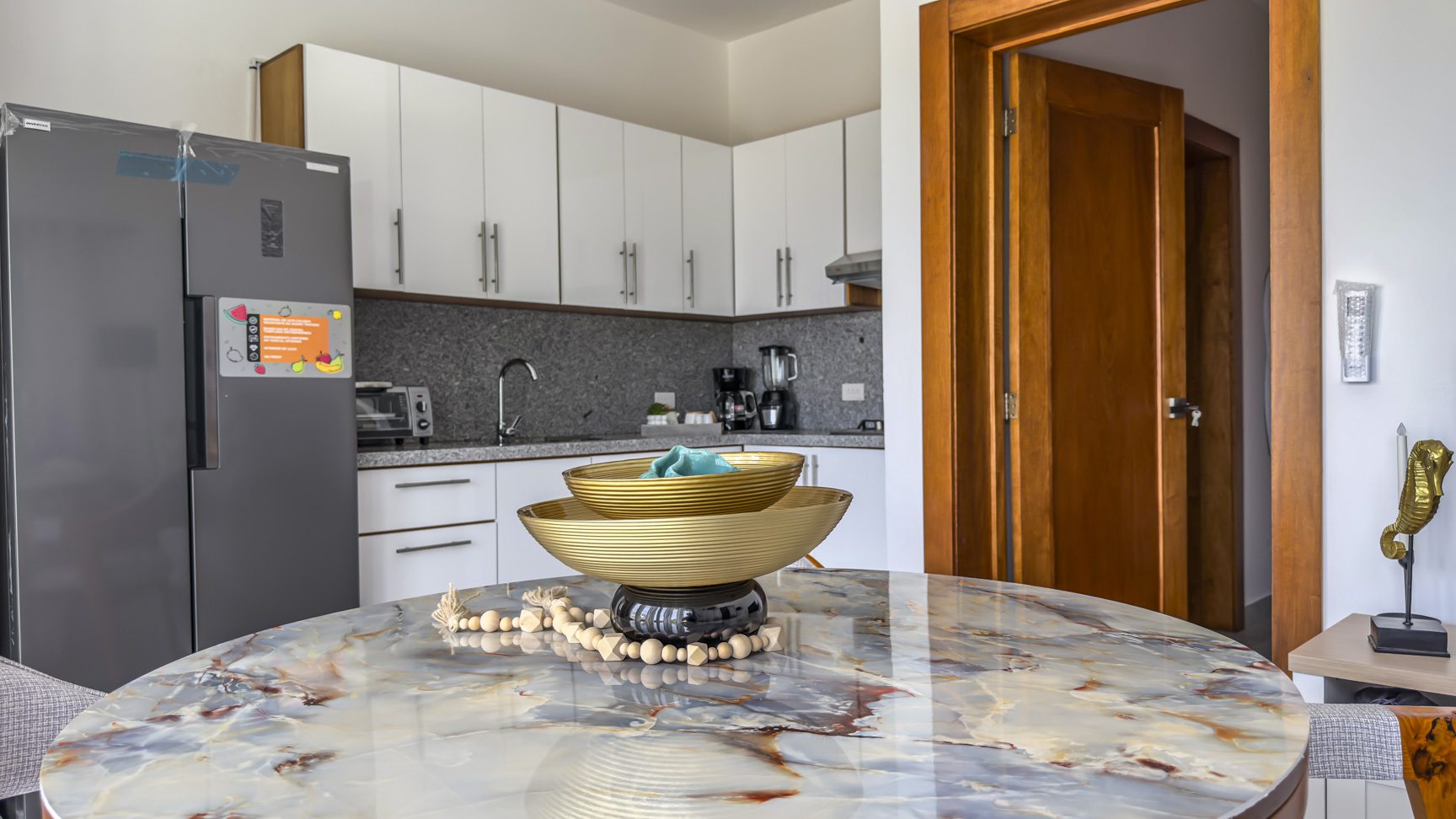 Modern kitchen with marble table and decorative bowls.