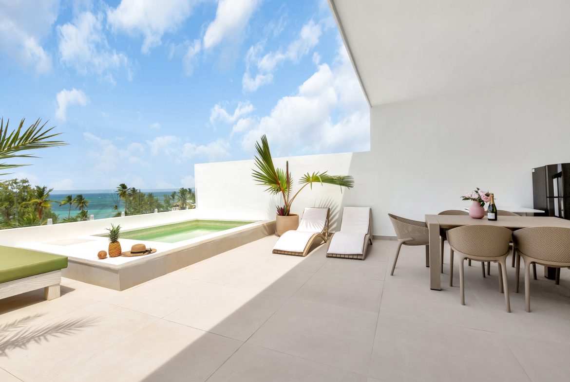 buyDRproperty Luxury balcony with pool, lounge chairs, dining table, and ocean view. Sosua Real Estate