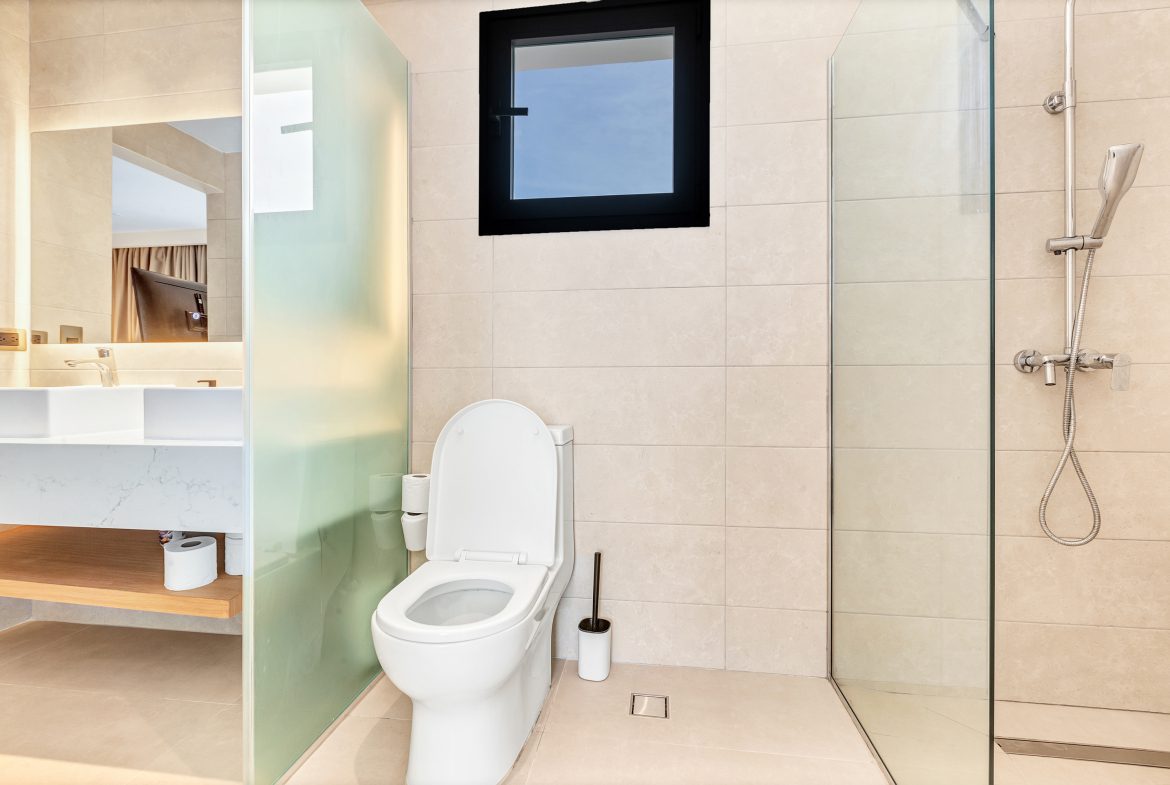 buyDRproperty Modern bathroom: toilet, shower, sink, and window with natural light. Sosua Real Estate