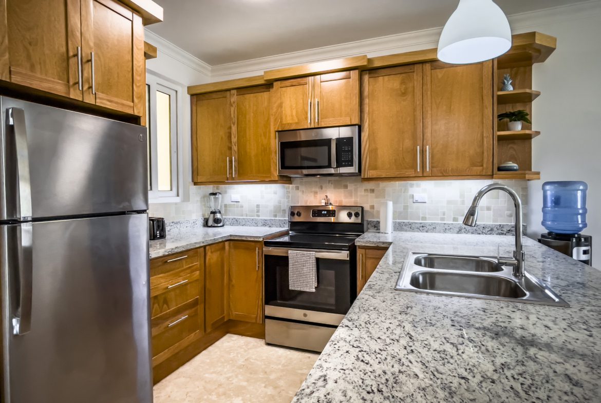 buyDRproperty Modern kitchen with stainless steel appliances, granite countertops, and wooden cabinets. Sosua Real Estate