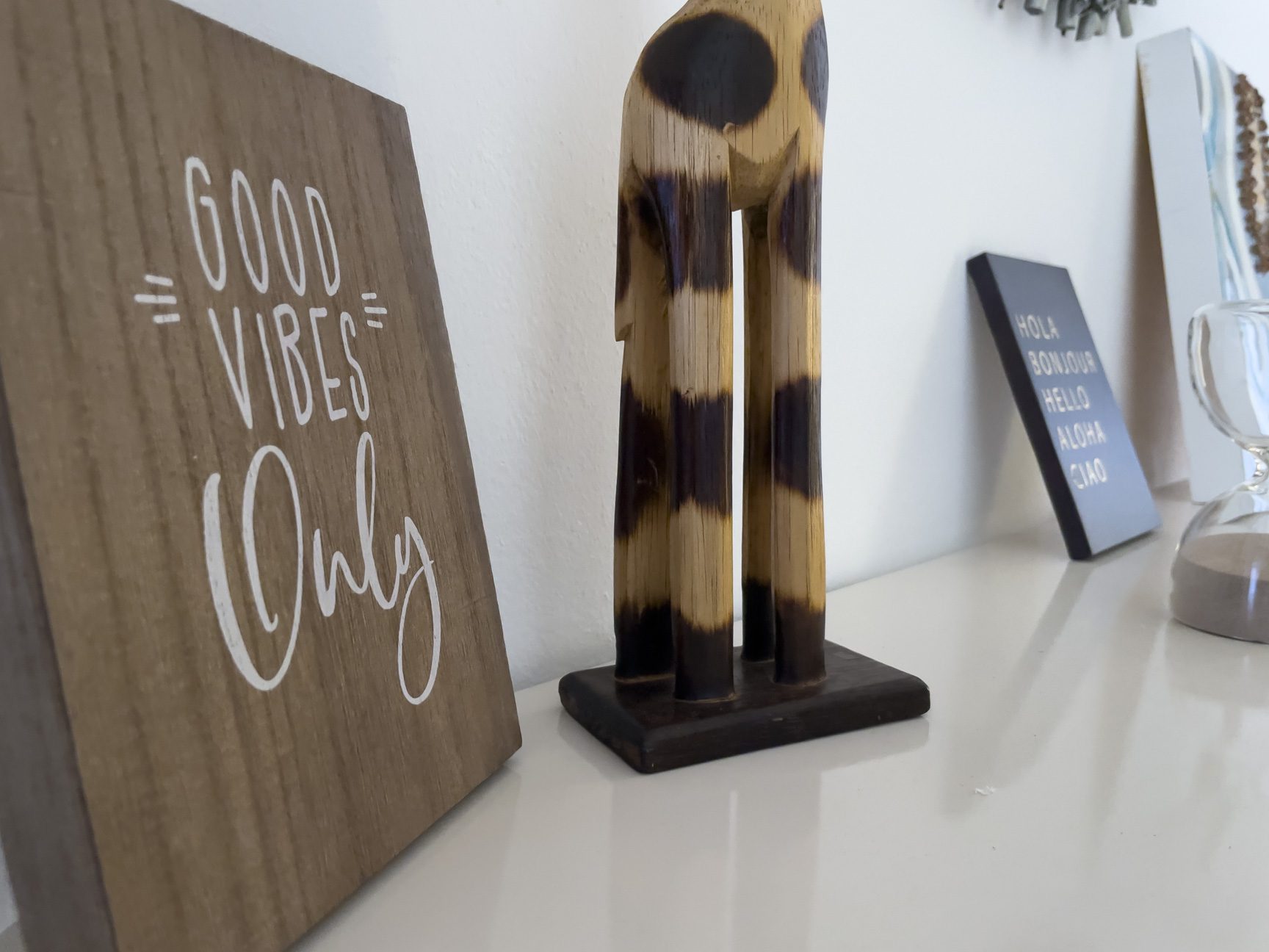 buyDRproperty Good Vibes Only sign, wooden giraffe, and travel-themed decor on a shelf. Sosua Real Estate