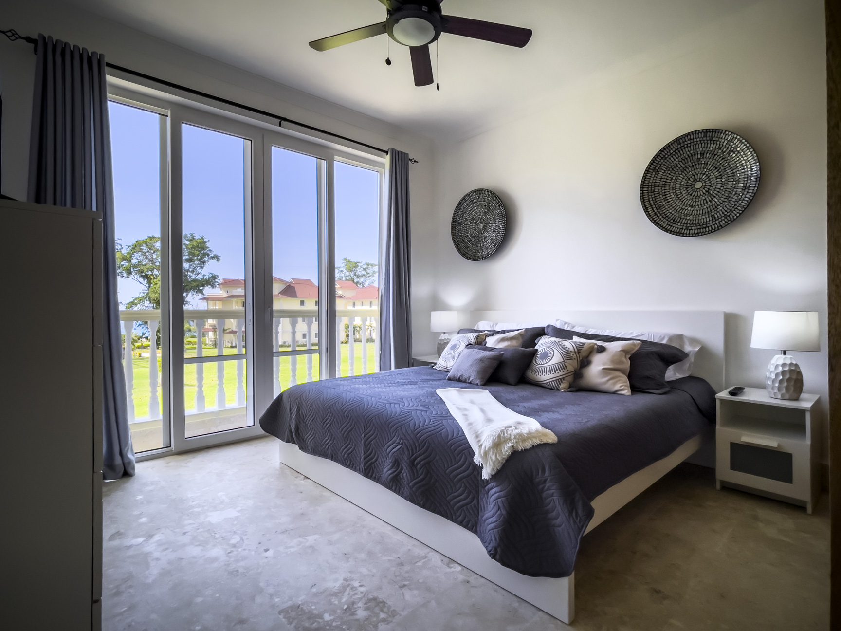 buyDRproperty Bright bedroom with a king bed, balcony, and woven wall art. Sosua Real Estate