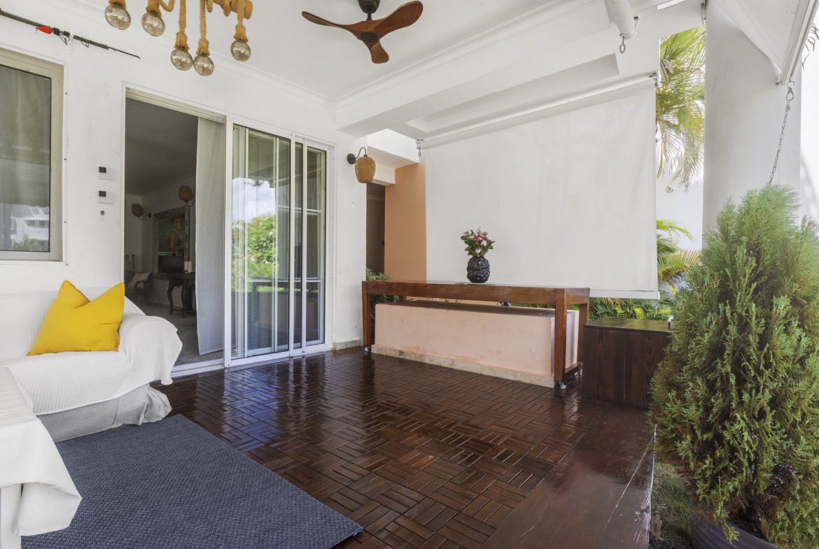 buyDRproperty Covered patio with dark wood flooring, white sofa, console table with flowers, and sliding glass doors. Sosua Real Estate