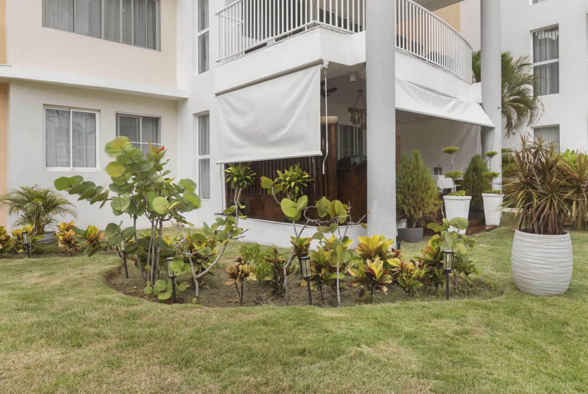 buyDRproperty Landscaped garden with tropical plants and modern building exterior. Sosua Real Estate