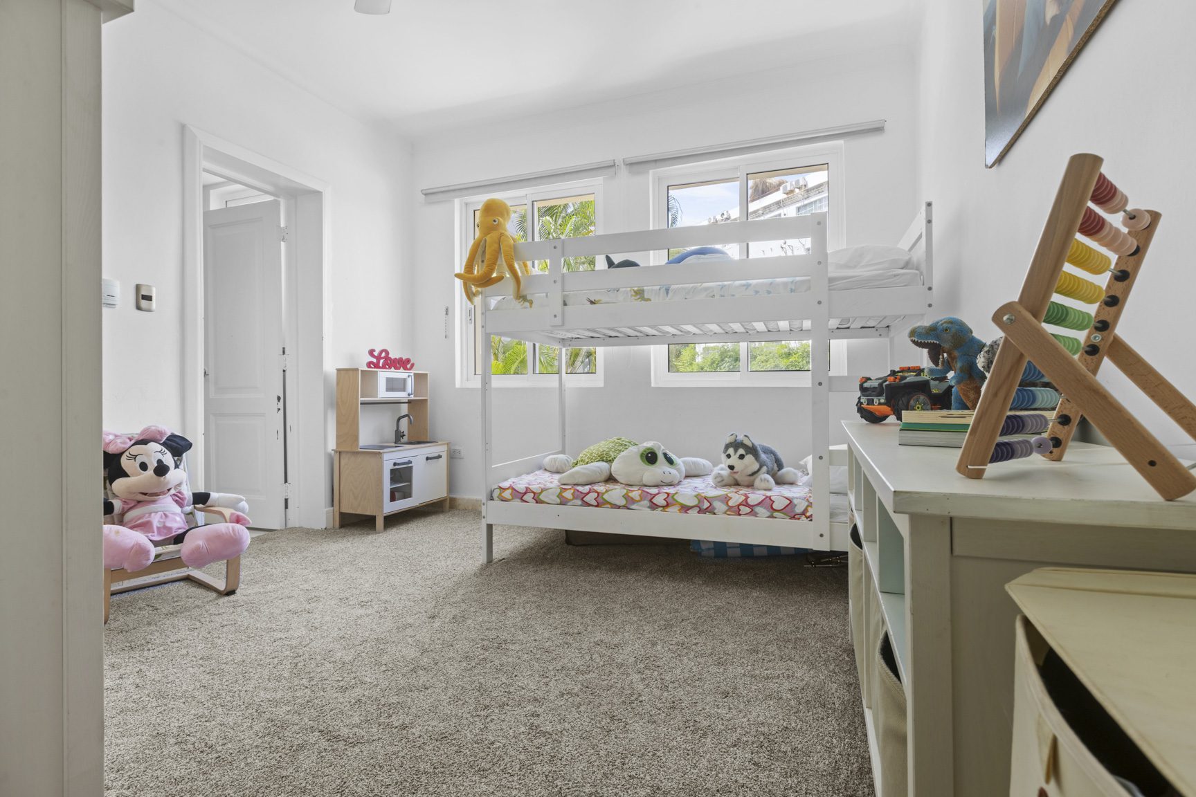 buyDRproperty Bright kids' room with white bunk beds, toys, and a play kitchen, creating a cheerful and playful atmosphere. Sosua Real Estate