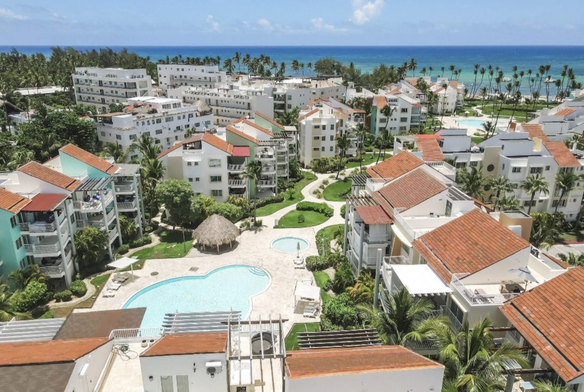 buyDRproperty Aerial view of a resort with pools and palm trees near the ocean. Sosua Real Estate