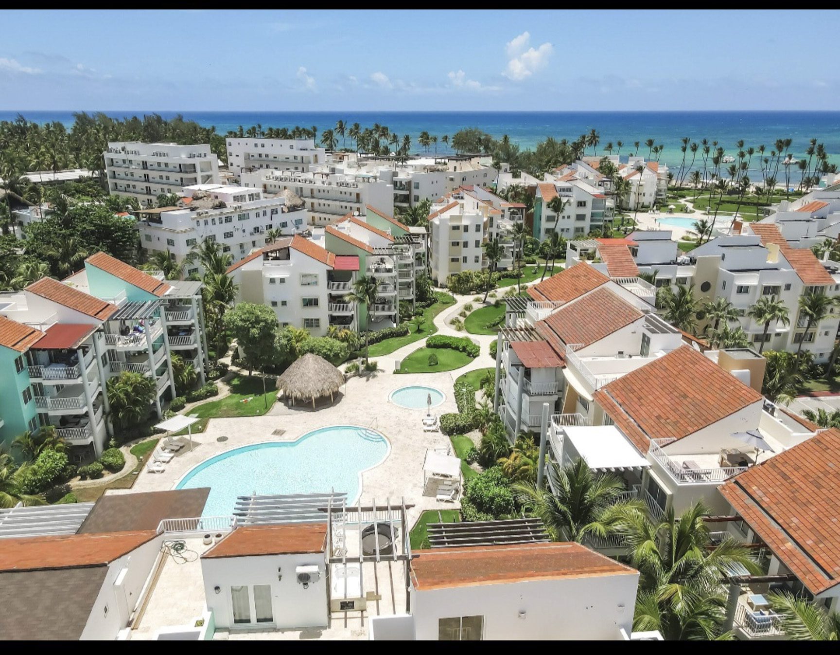 buyDRproperty Aerial view of a resort with pools and palm trees near the ocean. Sosua Real Estate